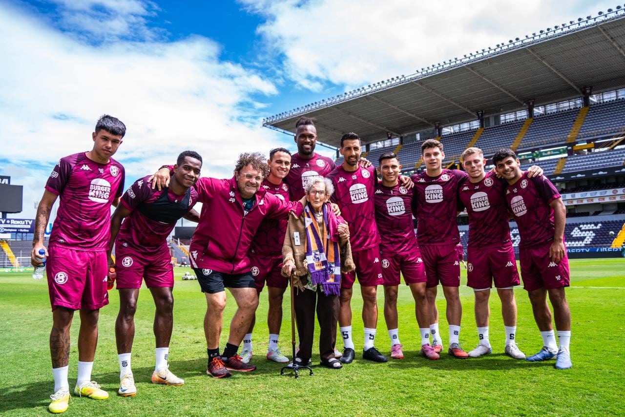 Rosario Quirós Roldán de 100 años visitó la práctica del Saprissa en el estadio Ricardo Saprissa, donde fue recibida por Mariano Torres, Kendall Waston y los otros jugadores.