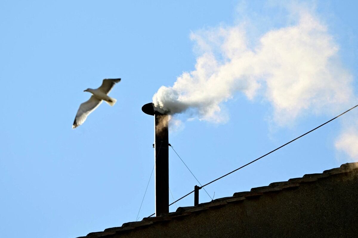 This photograph shows white smoke rising from the chinmey of the Sistine Chapel signaling that cardinals elected a new pope during their conclave in the Vatican on May 8, 2025. (Photo by Tiziana FABI / AFP)