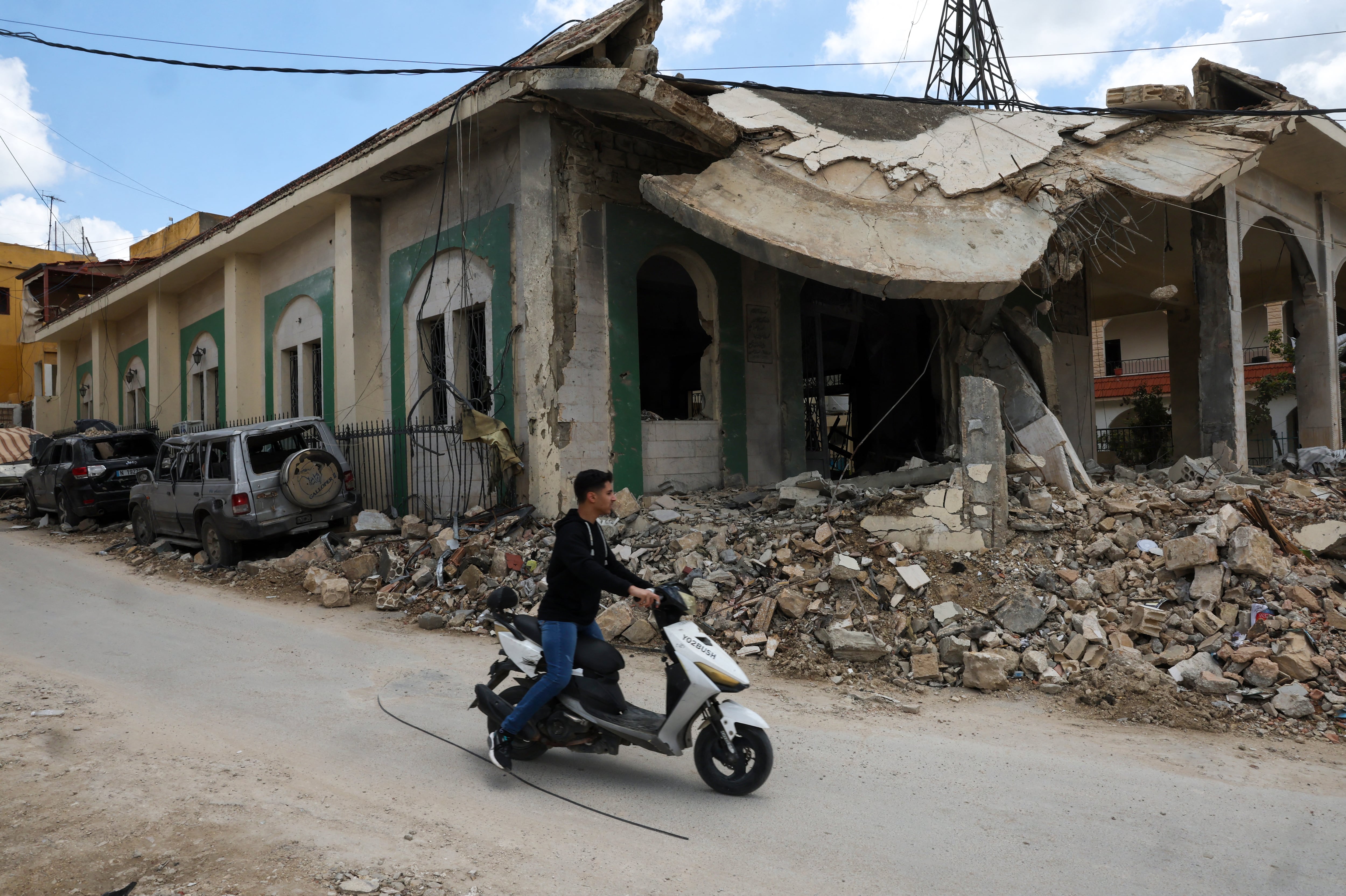 Un joven conduce una moto frente a una mezquita que fue blanco de un ataque israelí en la aldea sureña libanesa de Kfar Sir.