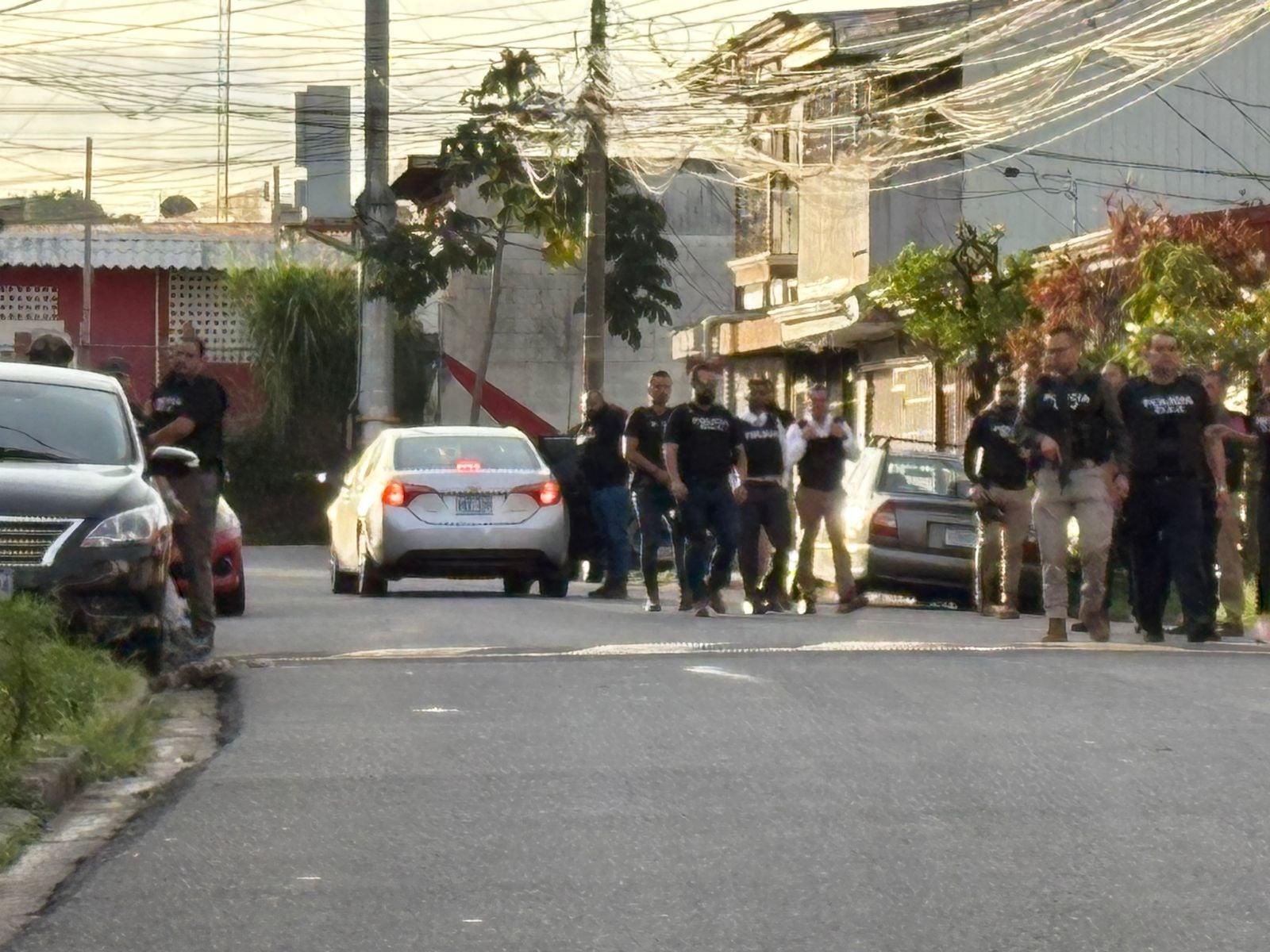 Una calle en un barrio residencial. Automóviles. Agentes del OIJ.
