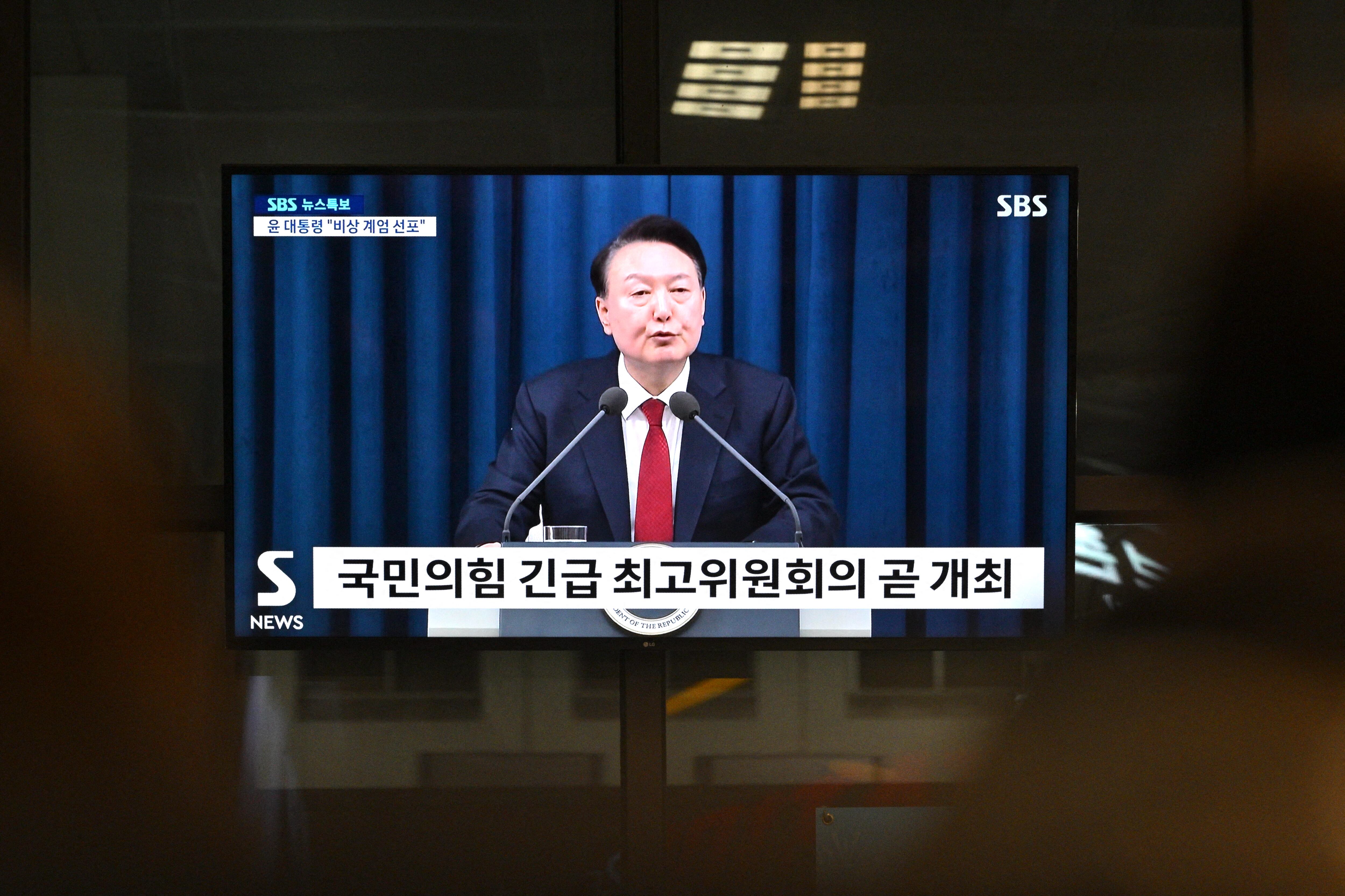 Pantalla de televisión muestra al presidente surcoreano Yoon Suk Yeol declarando la ley marcial en un discurso televisado el 3 de diciembre de 2024, en una estación de tren en Seúl.