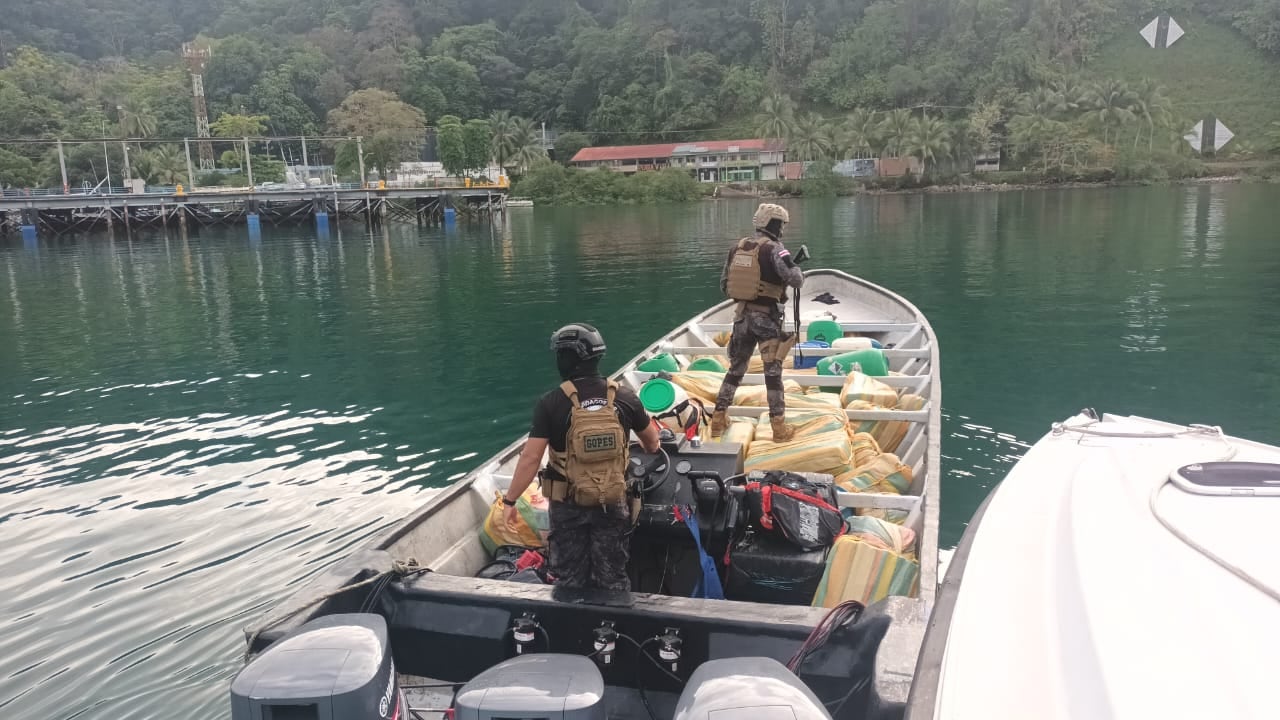 Dos agentes de seguridad inspeccionan un cargamento de droga en una lancha, reflejando el impacto del crimen organizado en Costa Rica.