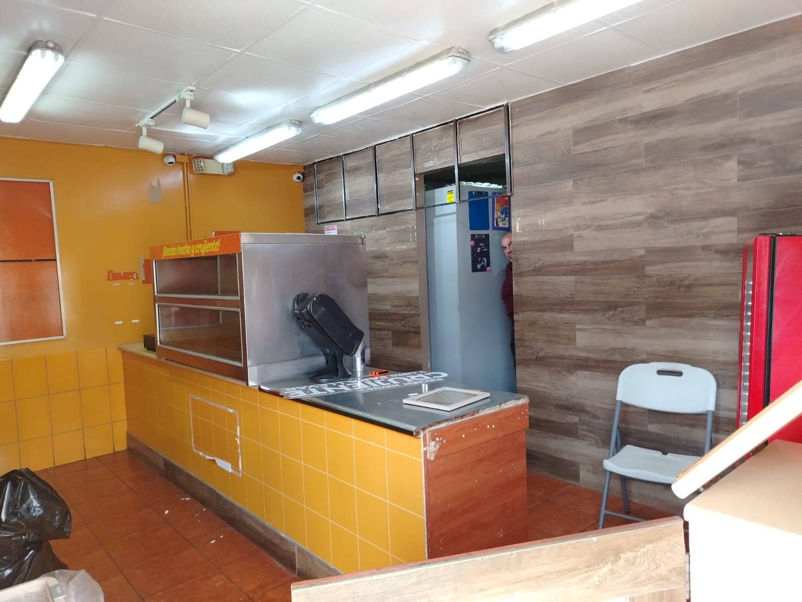 Interior vacío de restaurante Pollo Granjero cerrado en Costa Rica con mostrador sin atención y mobiliario tras salida de la empresa