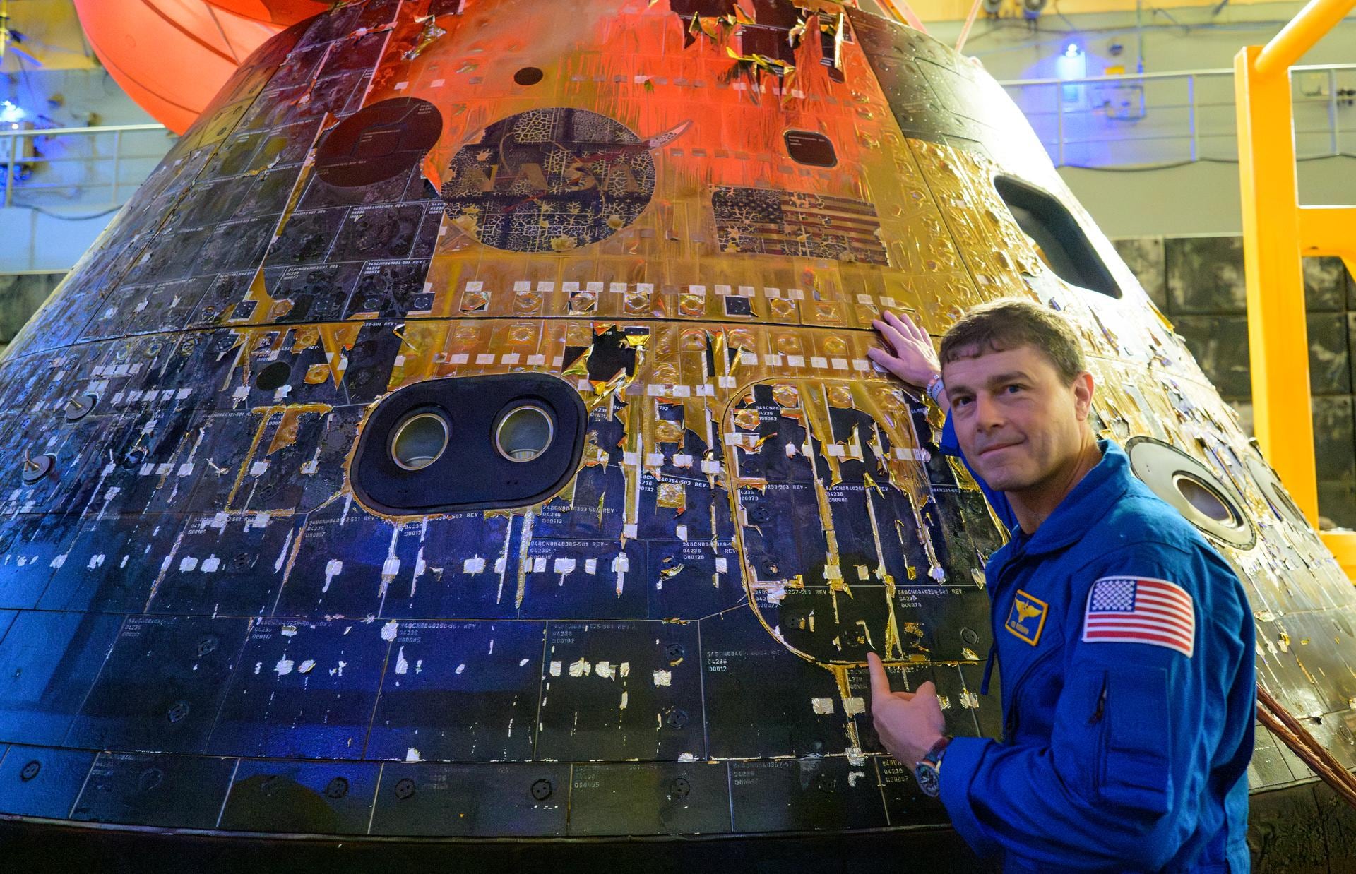 Reid Wiseman, comandante de Artemis II, señala el logotipo de la NASA y la bandera de Estados Unidos en el exterior de la nave Orion, tras el amerizaje de la misión en el océano Pacífico.