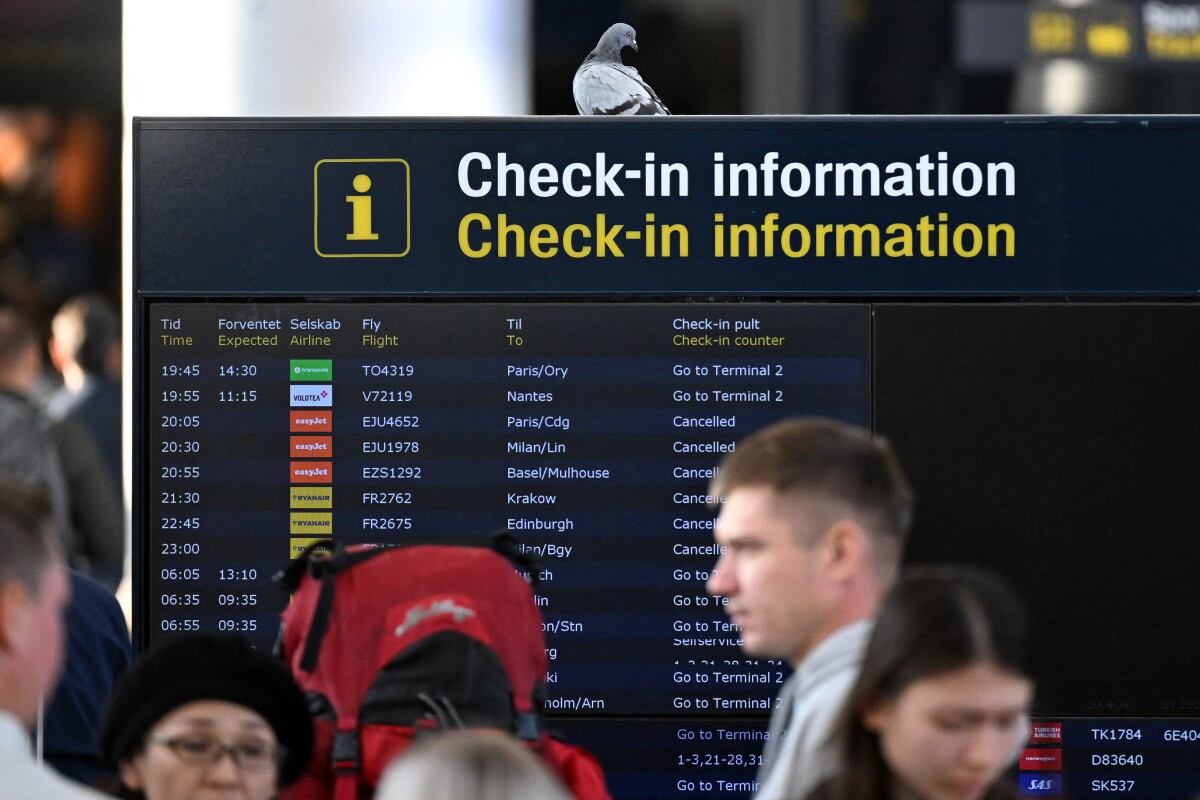 Passengers are seen in front of a bord displaying flight informations at the Copenhagen Airport in Copenhagen, Denmark, on September 23, 2025. Danish police said that whoever was responsible for flying large drones over Copenhagen airport appeared to have been knowledgeable, as flights resumed in Denmark and Norway capitals following a night of travel chaos. Airports in Copenhagen and Oslo reopened on Tuesday, September 23, hours after unidentified drones in their airspace caused dozens of flights to be diverted or cancelled, disrupting thousands of passengers. (Photo by Sergei GAPON / AFP)