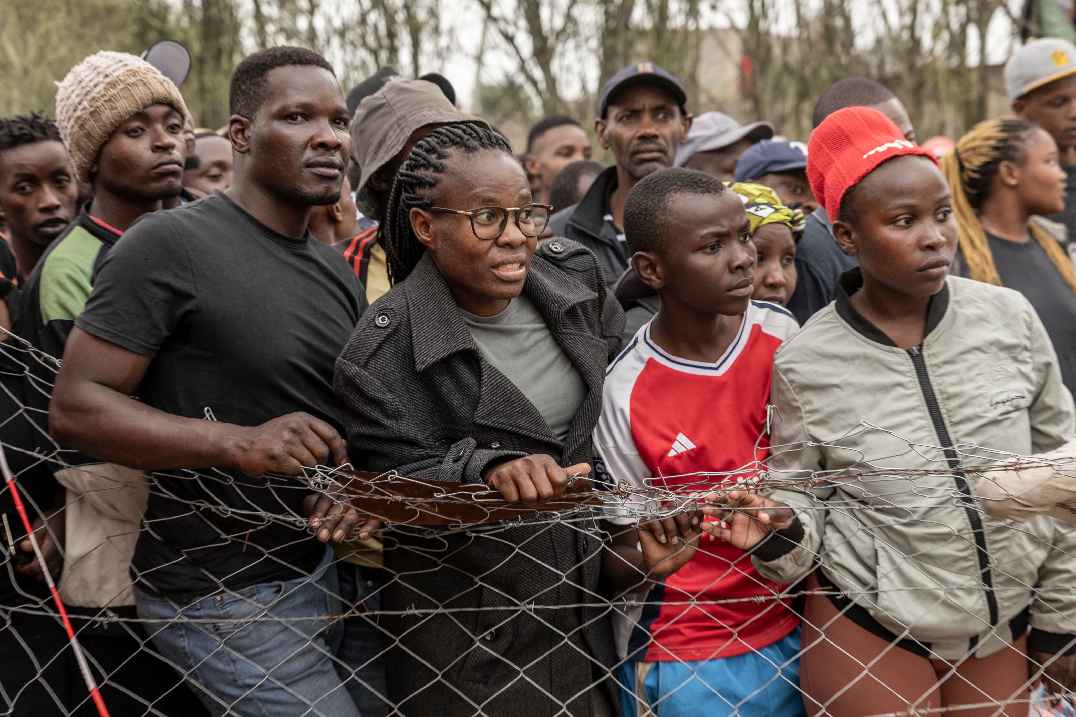 Onlookers react next to the scene where a Kenyan medical plane crashed, killing at least 6 people, on the outskirts of Nairobi on August 7, 2025. A medical light aircraft crashed into a small residential block near the Kenyan capital Nairobi, killing at least six people and injuring two seriously, a local official said on August 7, 2025.
