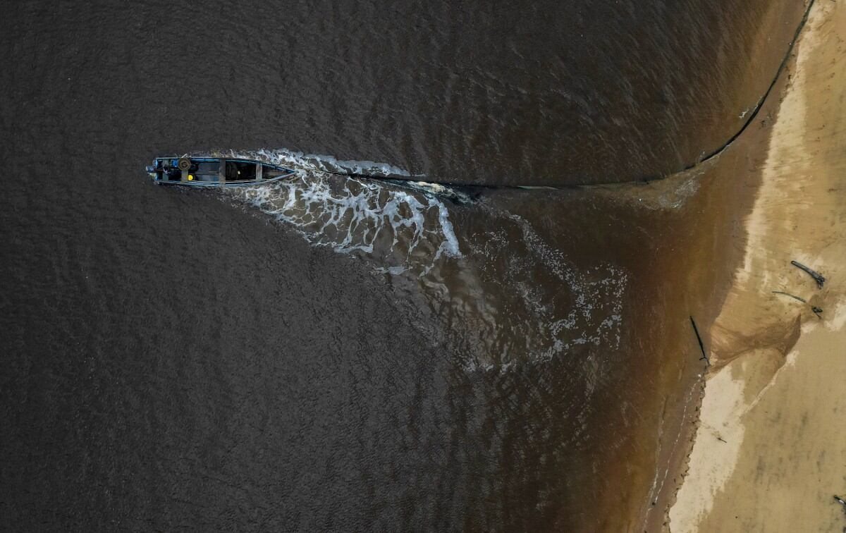 Esta vista aérea muestra a un pescador trabajando en un bote en la costa de la isla Braamsput en Paramaribo el 24 de mayo de 2025.