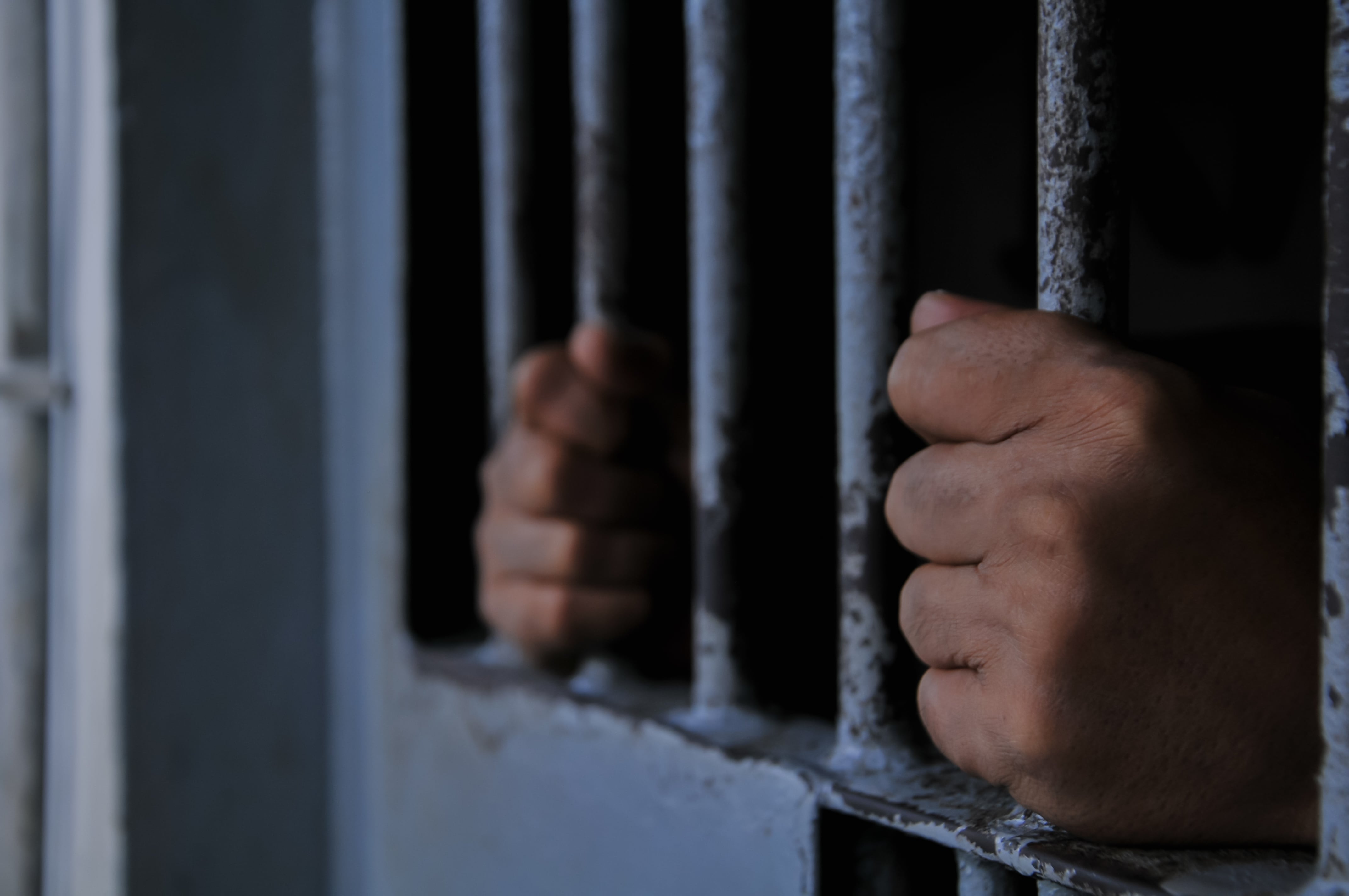 Manos de un privado de libertad, reo, preso, prisionero, sujetando los barrotes de una celda, cárcel, prisión, centro penal