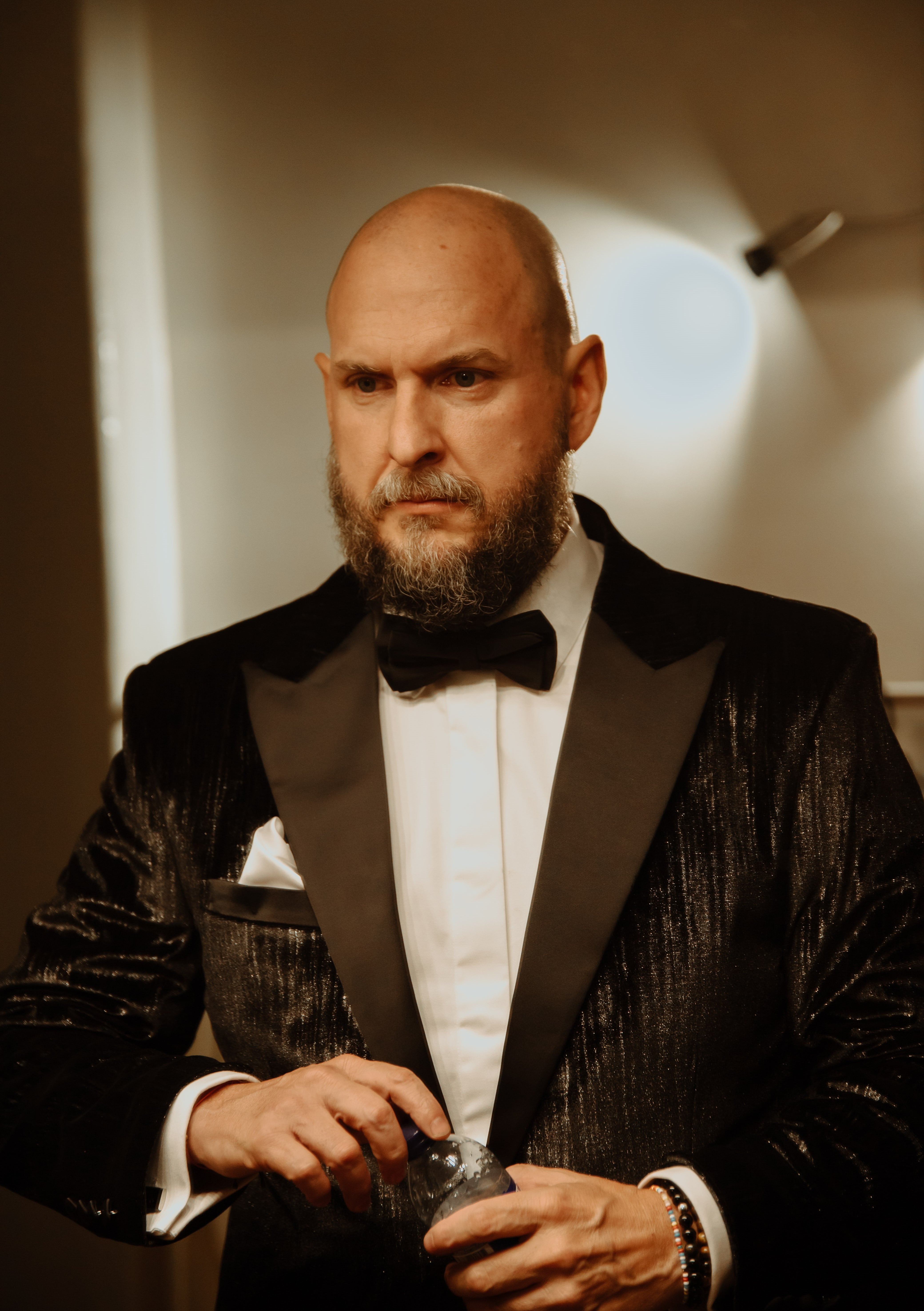 Imagen en primer plano del actor Andrés Parra, usa un traje oscuro y corbatín.