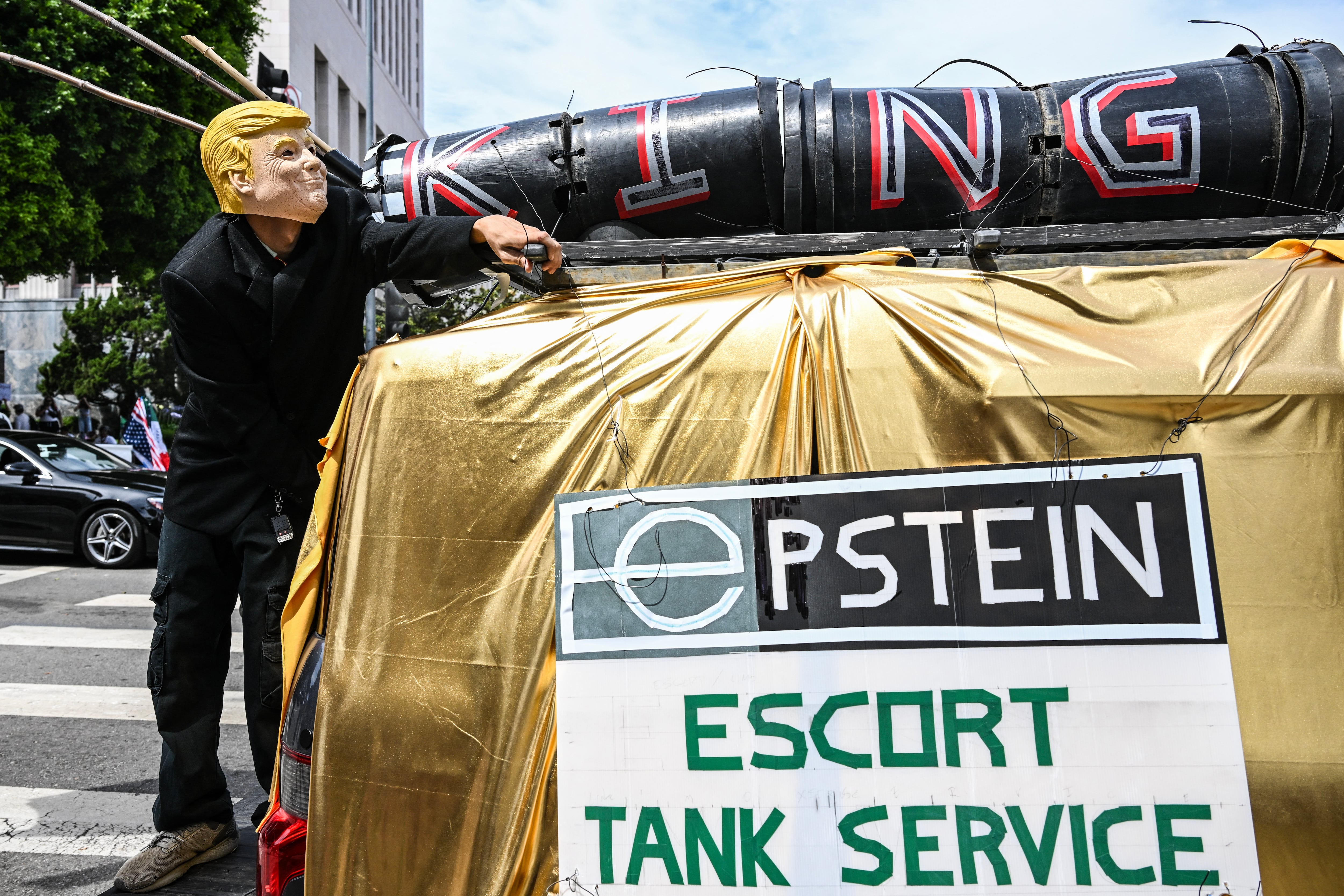 Un manifestante con una máscara de Trump se encuentra junto a un cartel que dice "Servicio de tanques de escolta de Epstein" durante la manifestación nacional "Sin Reyes" frente al Ayuntamiento de Los Ángeles el 14 de junio de 2025, el mismo día del desfile militar del presidente Trump en Washington, D.C. Decenas de miles de manifestantes se congregaron en todo el país el sábado contra Donald Trump antes de un gran desfile militar con motivo del 79.º cumpleaños del presidente estadounidense, mientras que el asesinato de un legislador demócrata subrayó las profundas divisiones en la política estadounidense. Los manifestantes de "Sin Reyes" salieron a las calles en Nueva York, Los Ángeles, Chicago, Filadelfia, Houston, Atlanta y cientos de otras ciudades de Estados Unidos para condenar lo que califican de extralimitación dictatorial de Trump. (Foto de RONALDO SCHEMIDT / AFP)
