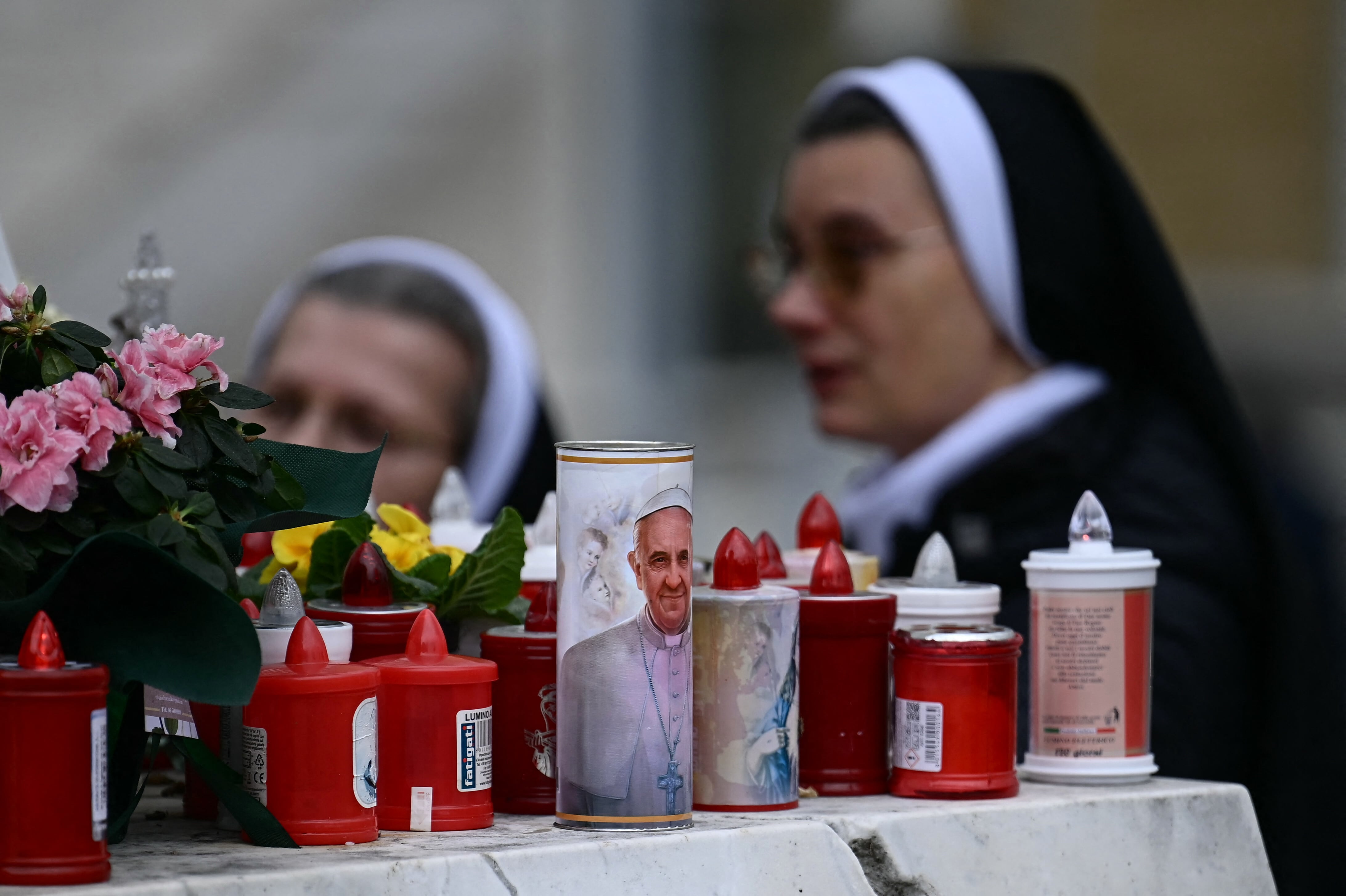 A candle with a portrait of Pope Francis is set at the feet of a statue of John Paul II outside the Gemelli hospital where Pope Francis is hospitalized in Rome, on February 20, 2025. Pope Francis passed another peaceful night in hospital, "got up and had breakfast in his armchair", the Vatican said on February 20, 2025. The 88-year-old was admitted to Rome's