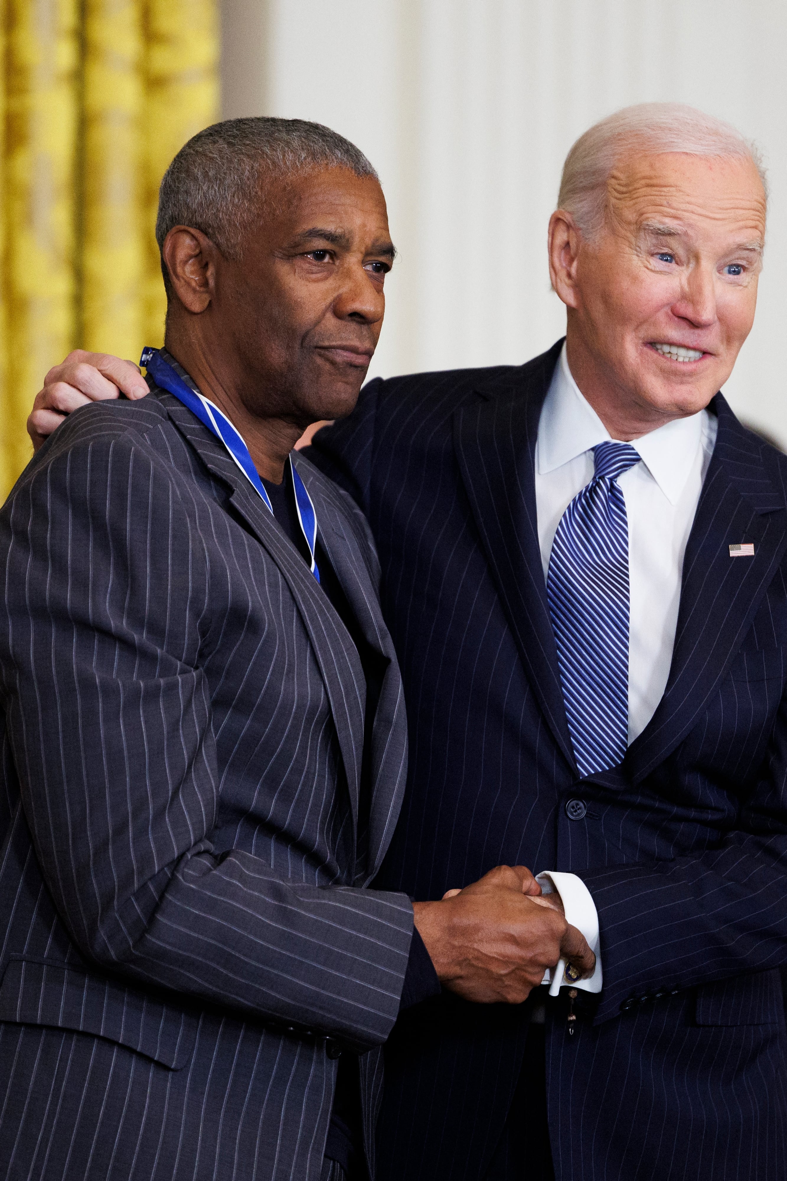 Imagen del actor Denzel Washington dándole la mano al presidente Joe Biden después de recibir la Medalla de la Libertad.