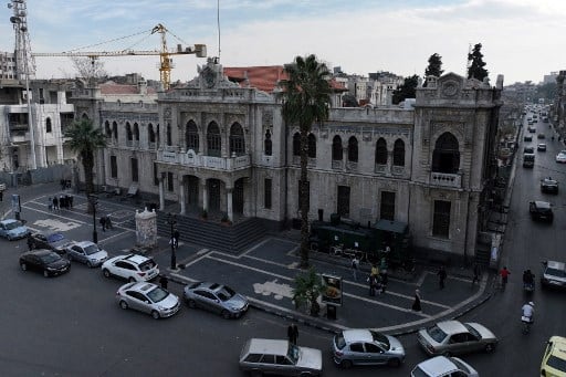 Edificio histórico en Siria rodeado de vehículos, representando la herencia cultural y las posibilidades de reconstrucción tras el declive del régimen de Bashar al Asad.