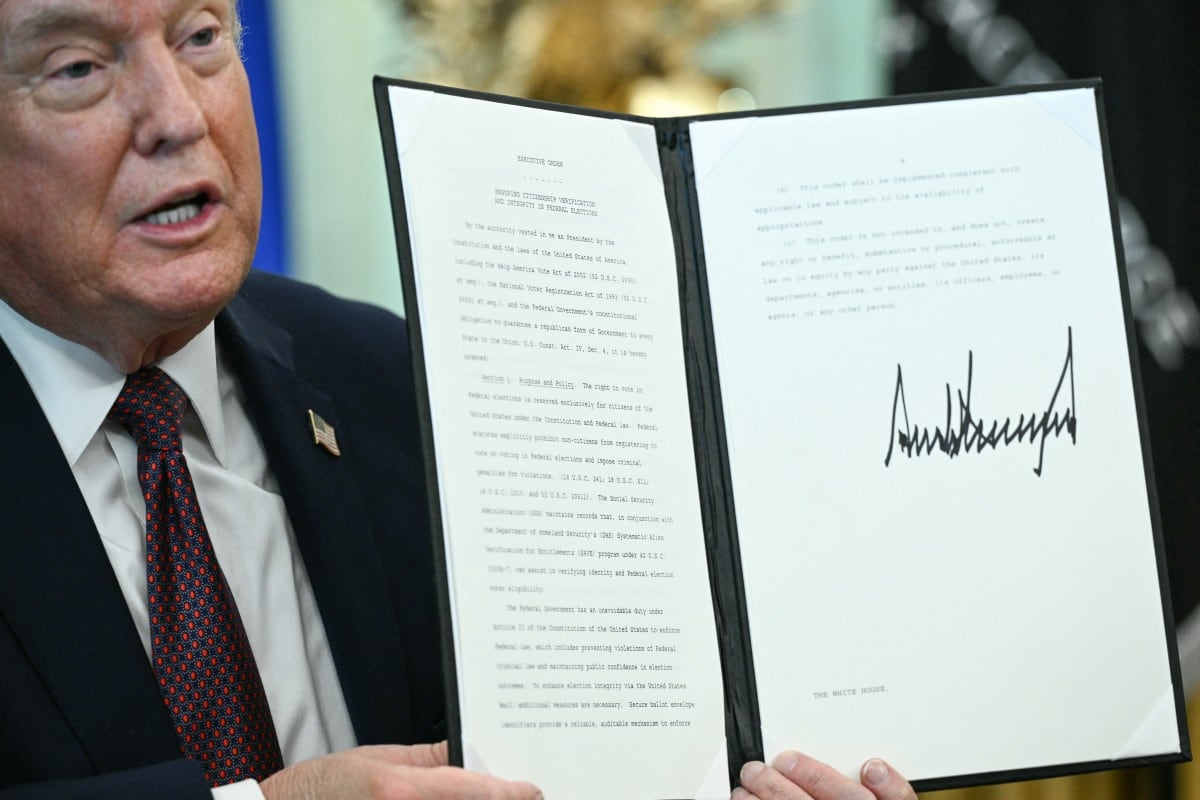 El presidente de Estados Unidos, Donald Trump, muestra una orden ejecutiva que firmó para restringir el voto por correo de cara a las elecciones de mitad de período, en el Despacho Oval de la Casa Blanca, en Washington D. C., el 31 de marzo de 2026.