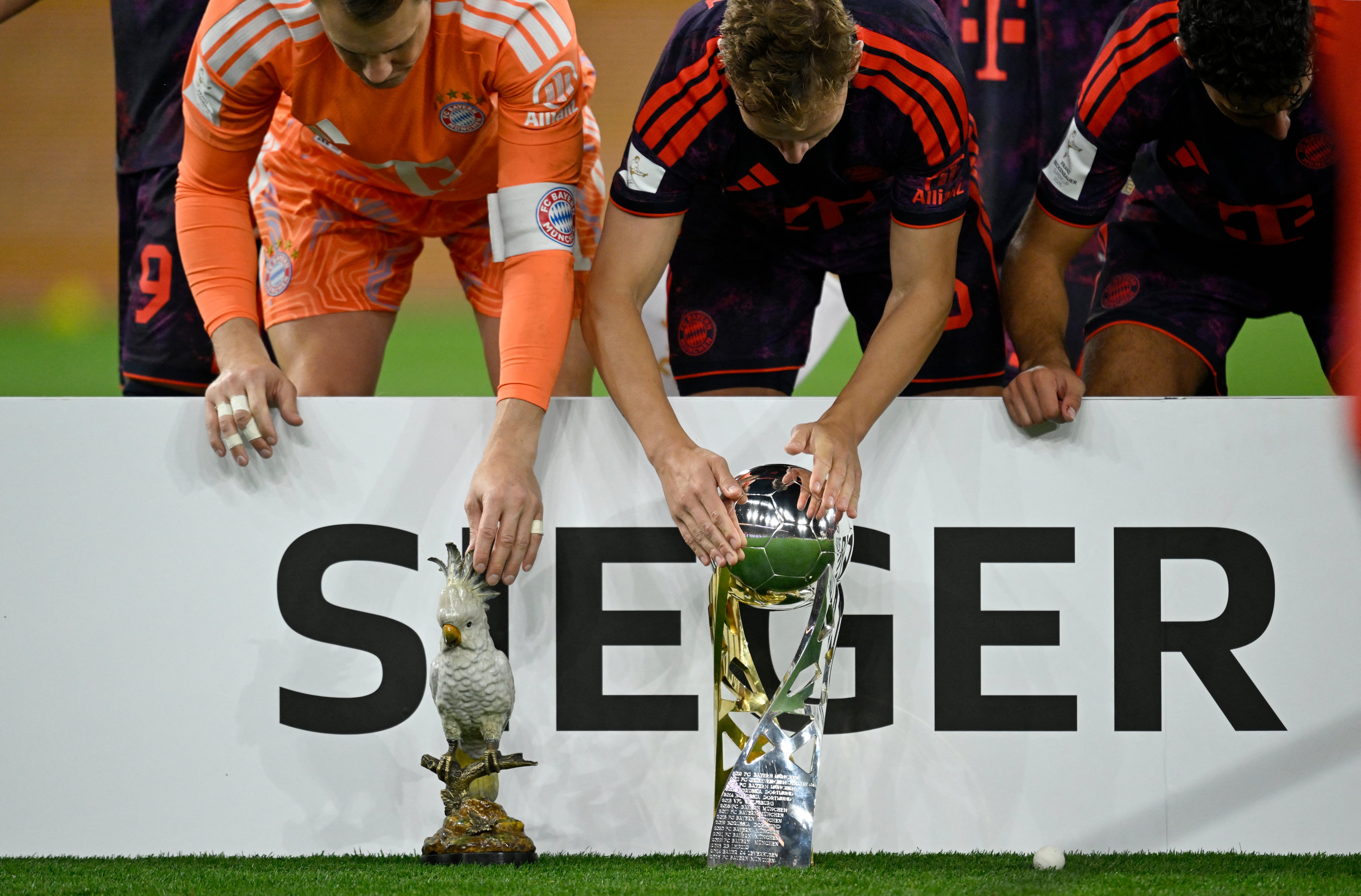 Los jugadores del Bayern Múnich acarician el trofeo y su talismán, una cacatúa de cerámica, como parte de la premiación de la Supercopa de Alemania.