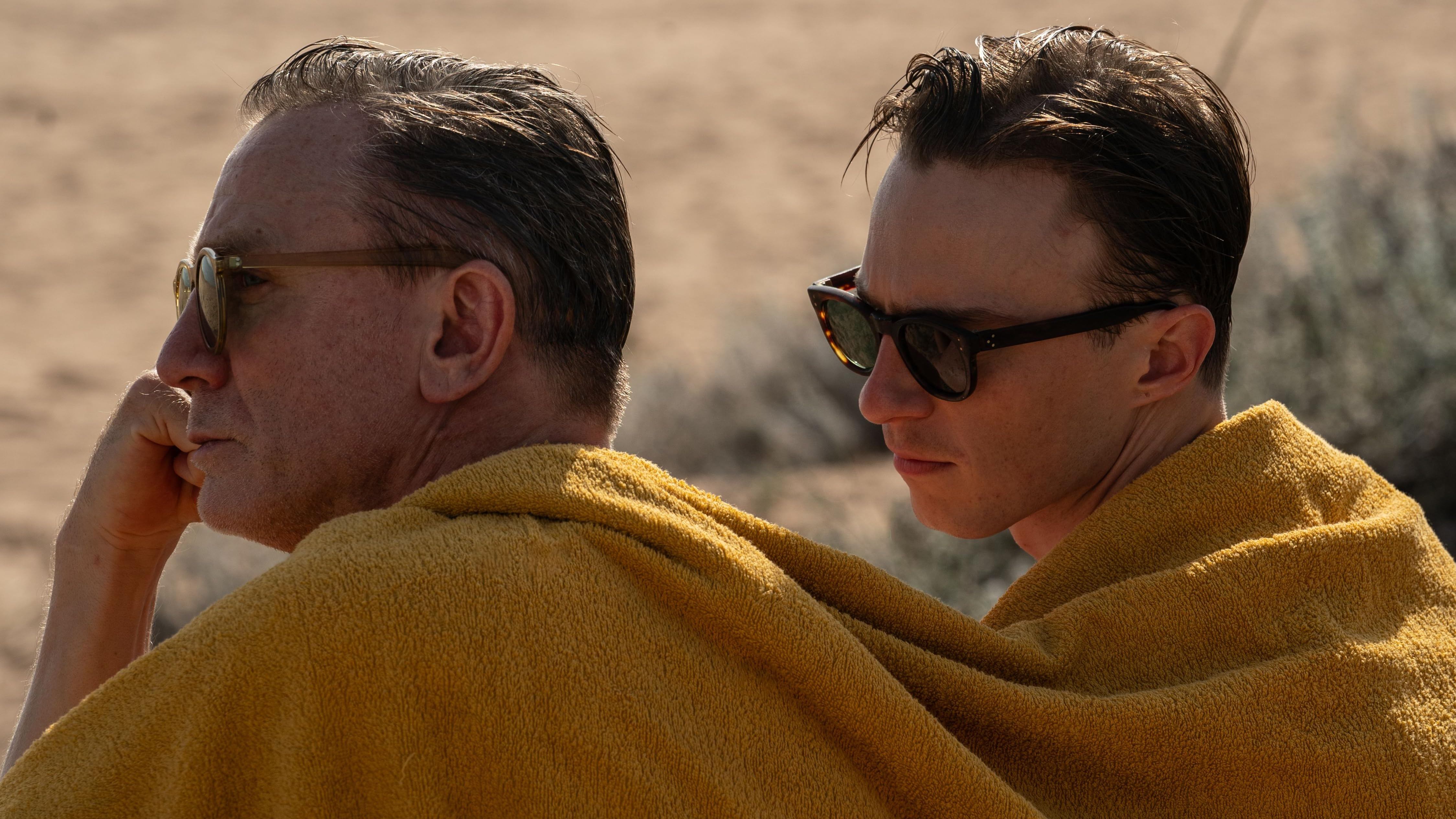 Escena de la película 'Queer' en la que Daniel Craig y Drew_Starkey están sentados mirando al horizonte arropados por un paño amarillo