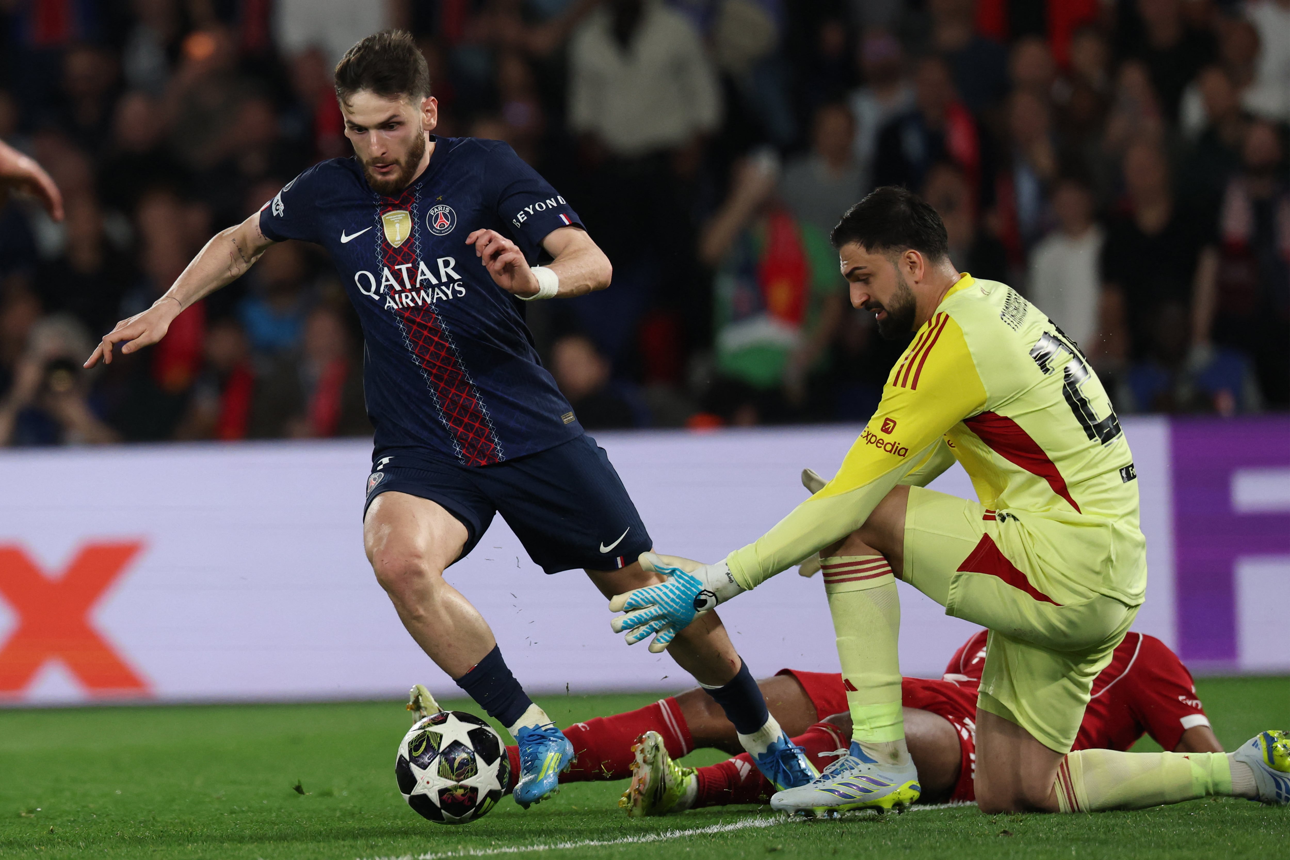 El delantero del PSG Khvicha Kvaratskhelia controla el balón ante el arquero Giorgi Mamardashvil, del Liverpool, camino a anotar en este duelo por la Champions