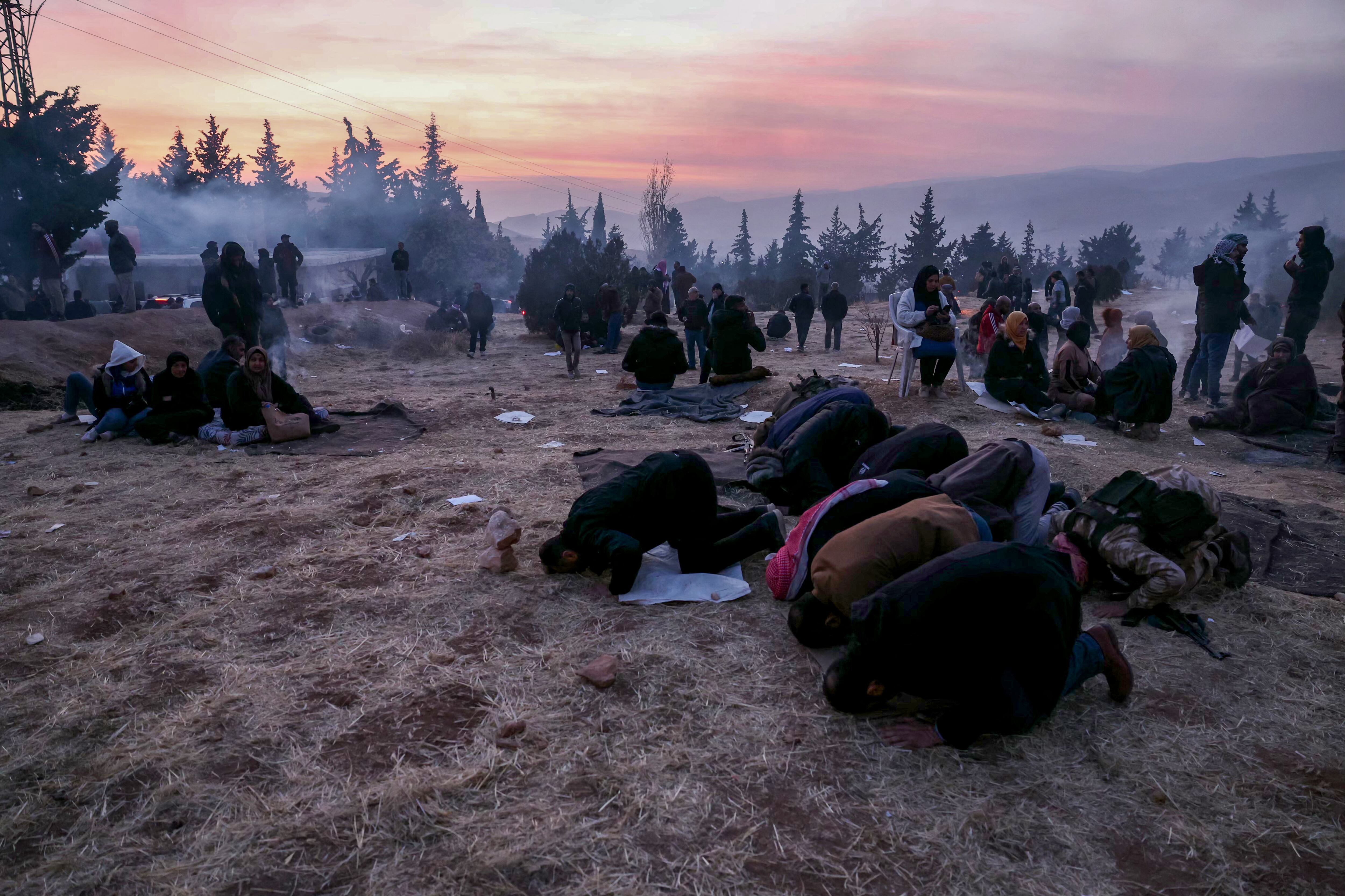Grupo de personas rezando al atardecer cerca de la prisión de Saydnaya, en un ambiente cargado de incertidumbre el 9 de diciembre de 2024.