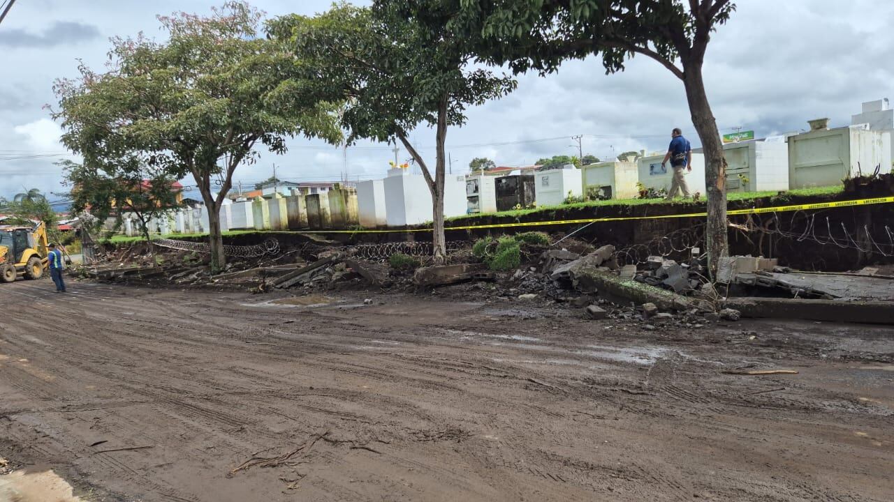 Con tractores se removieron los escombros de la tapia perimetral oeste del cementerio de Tibás que la noche del viernes colapsó, cayó sobre la acera y derribó varios árboles. Foto: Cortesía.