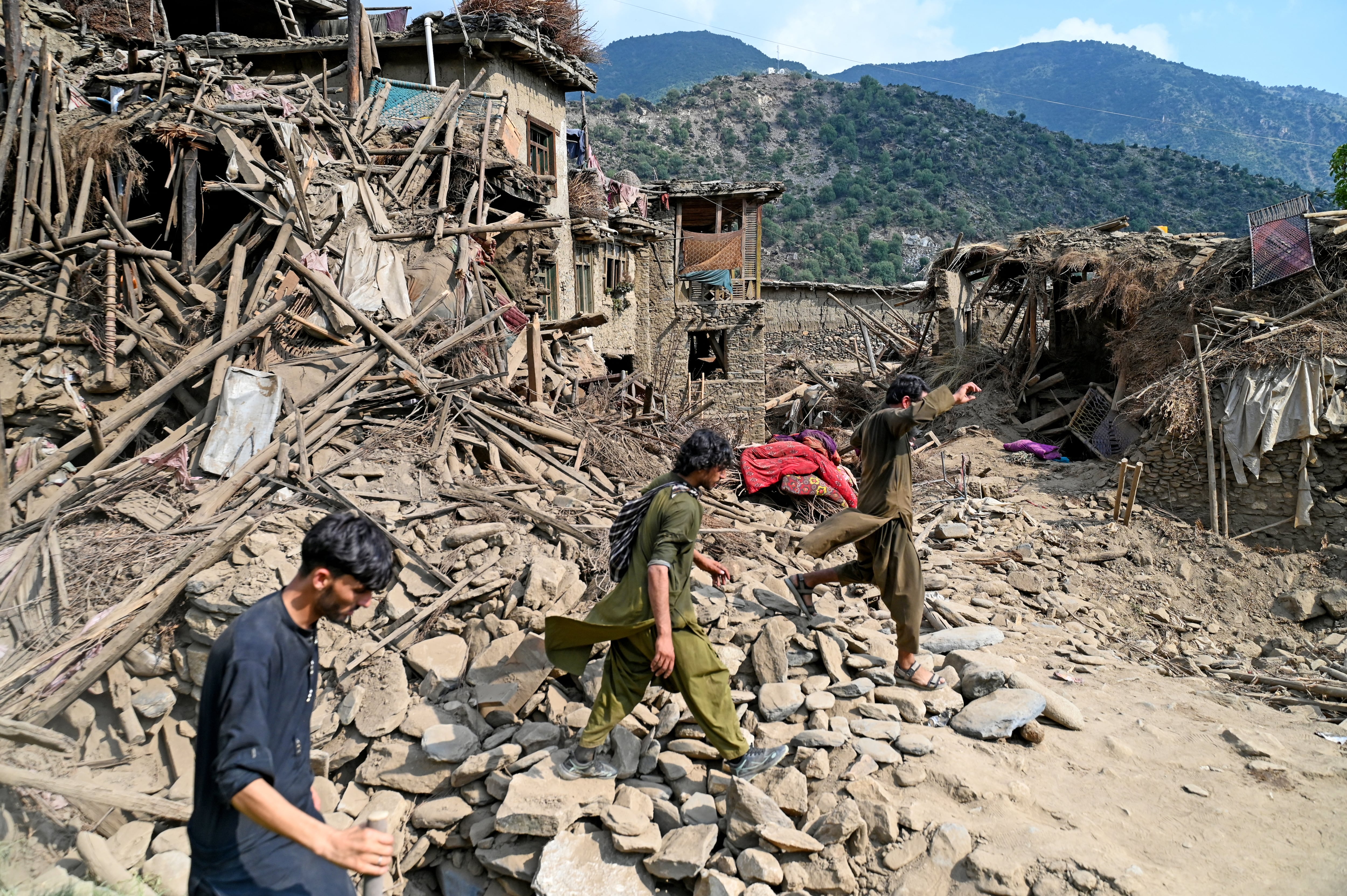 Afganos junto a casas dañadas tras los terremotos en la aldea de Mazar Dara, en el distrito de Nurgal, provincia de Kunar, en el este de Afganistán este lunes. Fotografía: