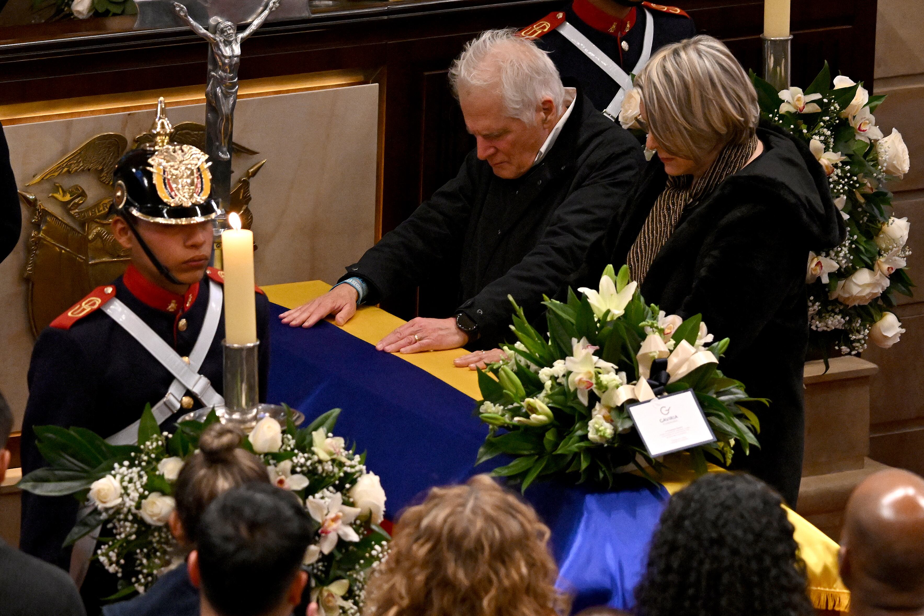 Miguel Uribe Londono (C), the father of late Colombian presidential candidate Miguel Uribe Turbay, puts his hands on the coffin lying in state at Congress in Bogota on August 11, 2025. Colombian presidential candidate Miguel Uribe died two months after being shot in the head at a campaign event, his wife announced early August 11, 2025. The legislator's condition had returned to critical after he suffered a new brain hemorrhage related to the assassination attempt during a rally on June 7, in which he was shot three times, twice in the head. (Photo by Raul ARBOLEDA / AFP)
