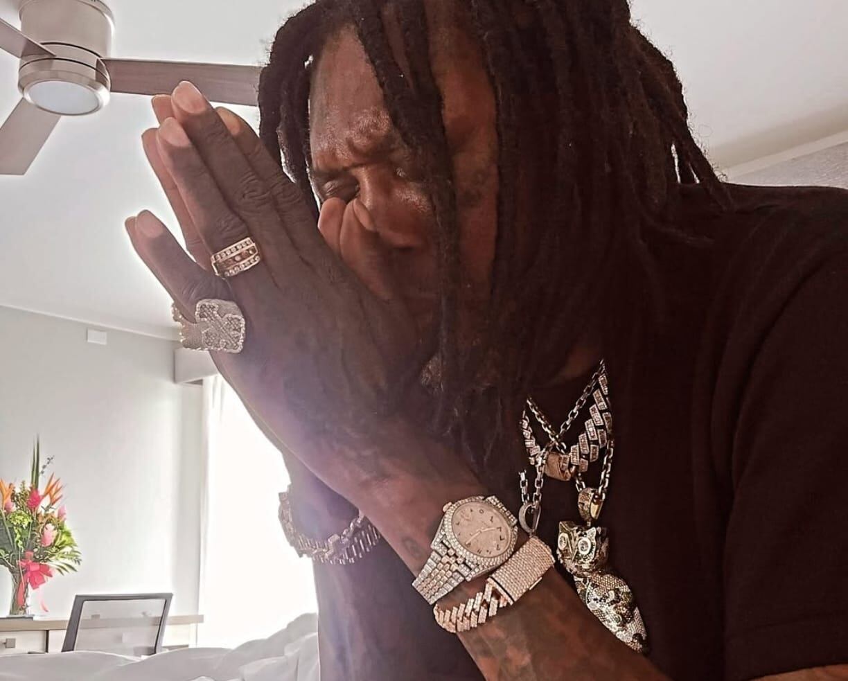 Vybz Kartel con las manos en el rostro como si estuviera orando.