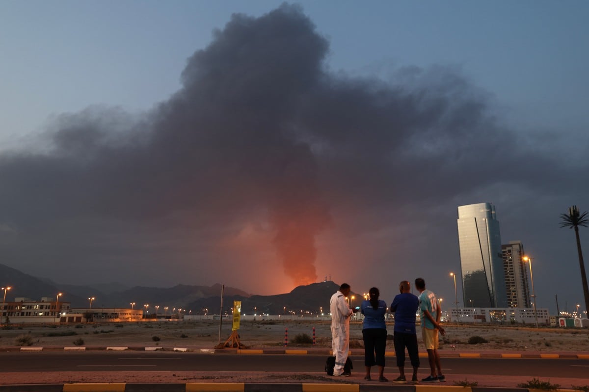 Trabajadores extranjeros observan una densa columna de humo negro que se eleva tras una explosión en la zona industrial de Fujairah, el 3 de marzo de 2026.