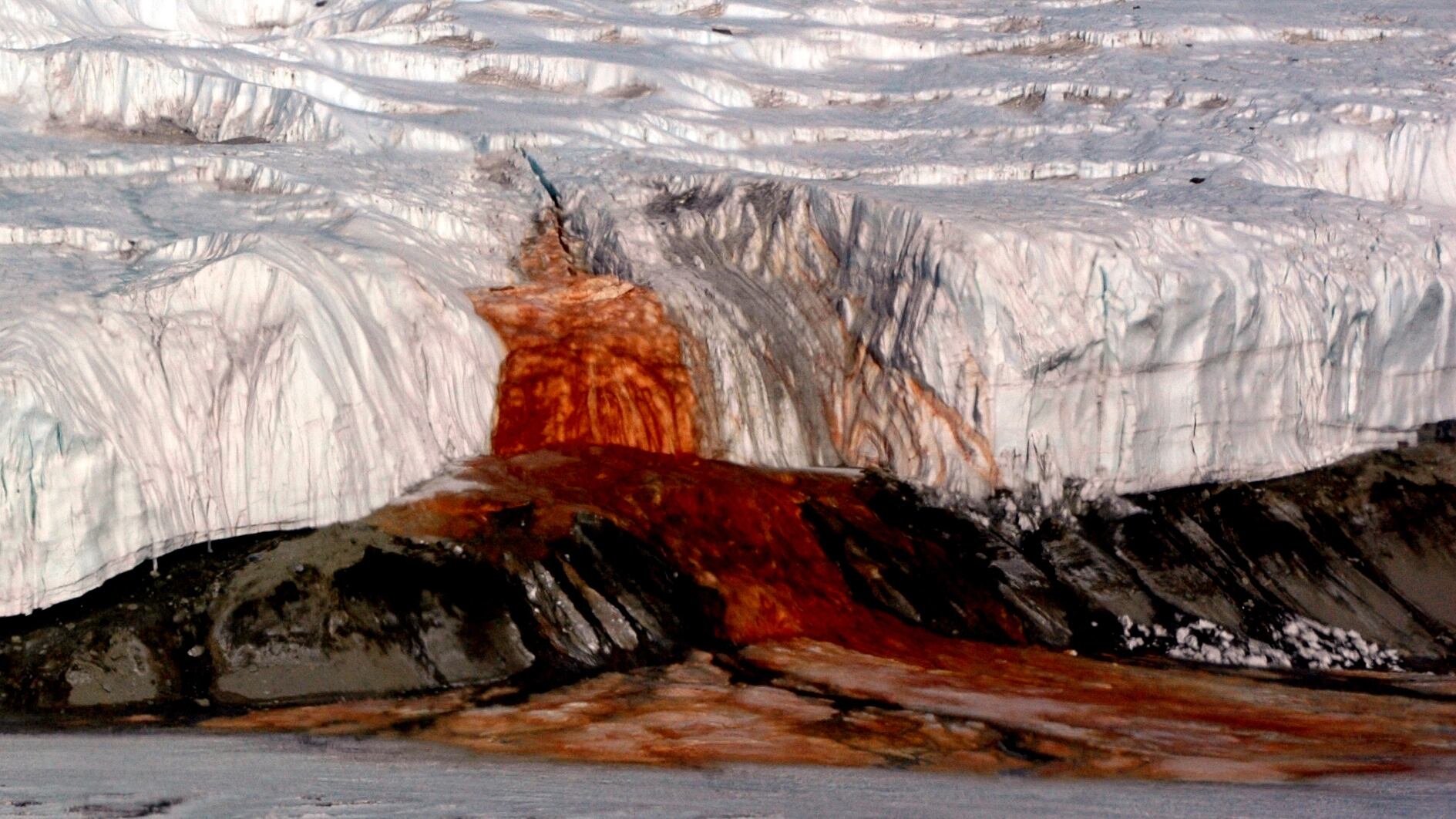 The Blood Falls seeps from the end of the Taylor Glacier into Lake Bonney. The tent at left provides a sense of scale for just how big the phenomenon is. Scientists believe a buried saltwater reservoir is partly responsible for the discoloration, which is a form of reduced iron.