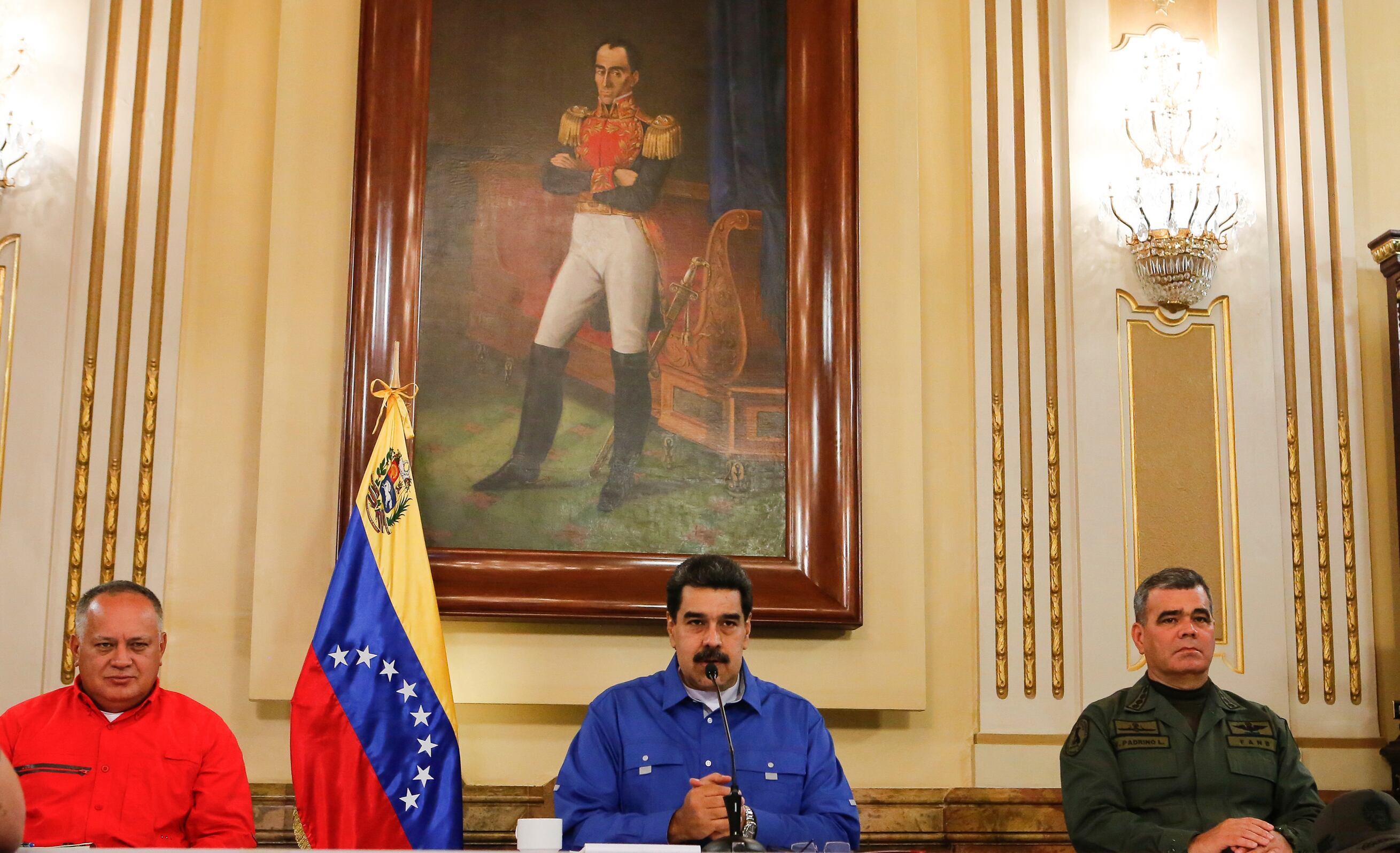 Nicolás Maduro sentado junto a funcionarios militares y civiles en el Palacio de Miraflores, con la bandera de Venezuela y un retrato de Simón Bolívar al fondo.