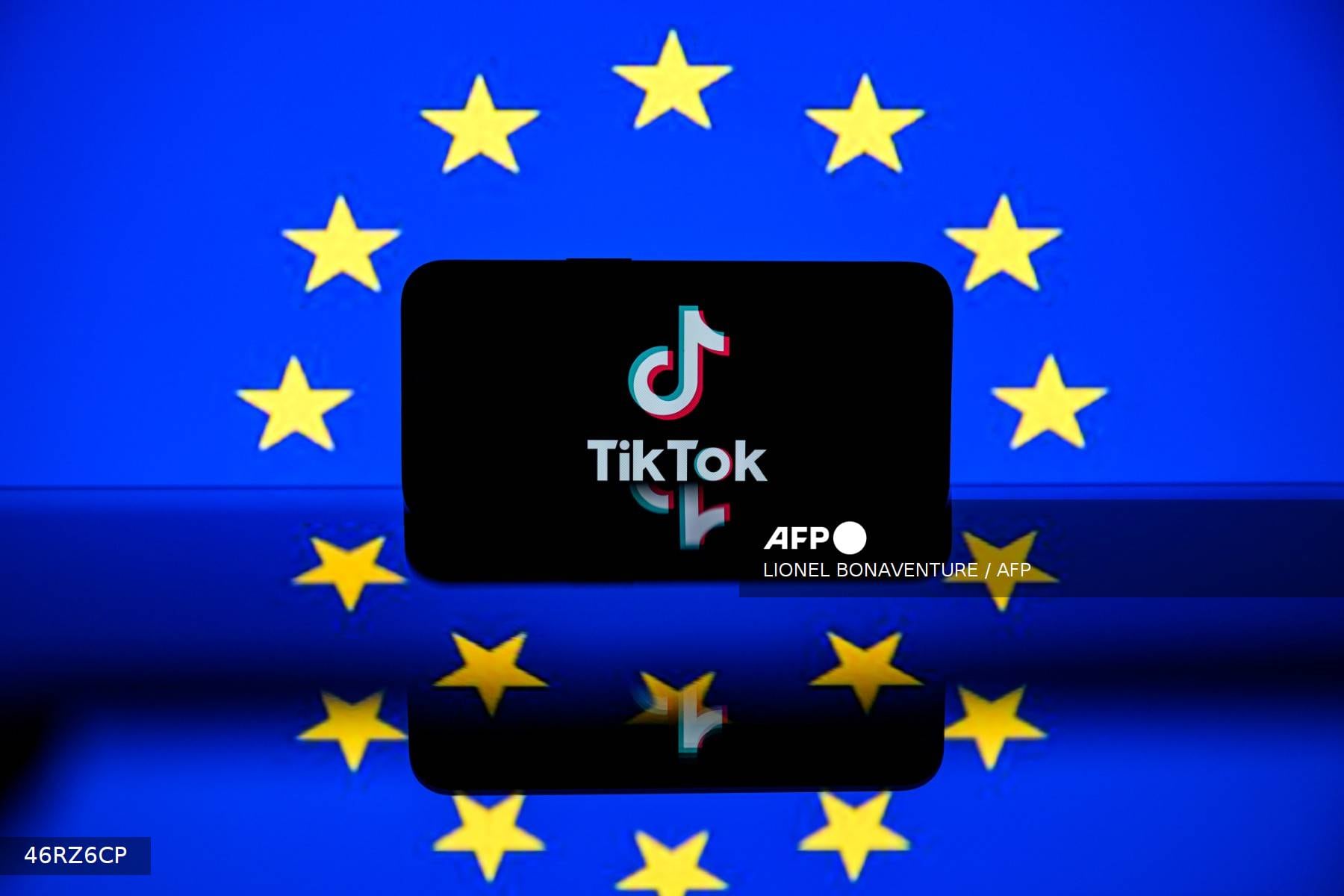 El logo de TikTok sobre una pantalla frente a la bandera de la Unión Europea. La Comisión Europea acusa a TikTok de violar la Ley de Servicios Digitales por falta de transparencia en su sistema publicitario.