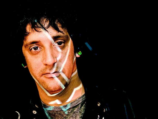 Primer plano del presentador Luis Lauretto, con un patrón de luces que le dibuja líneas sobre la cara.