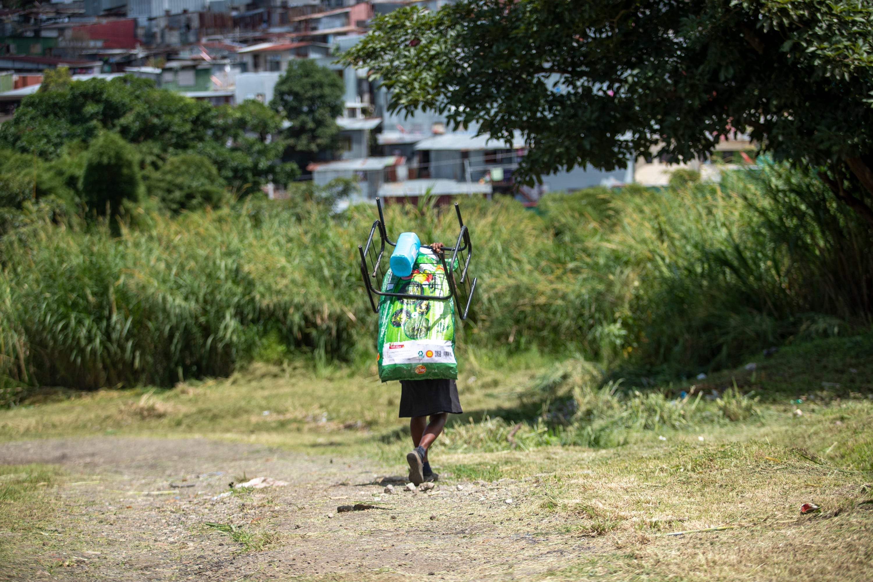 Joven cargando una bolsa de suministros en una zona rural, simbolizando la exclusión social y su impacto en el reclutamiento por narcotráfico.