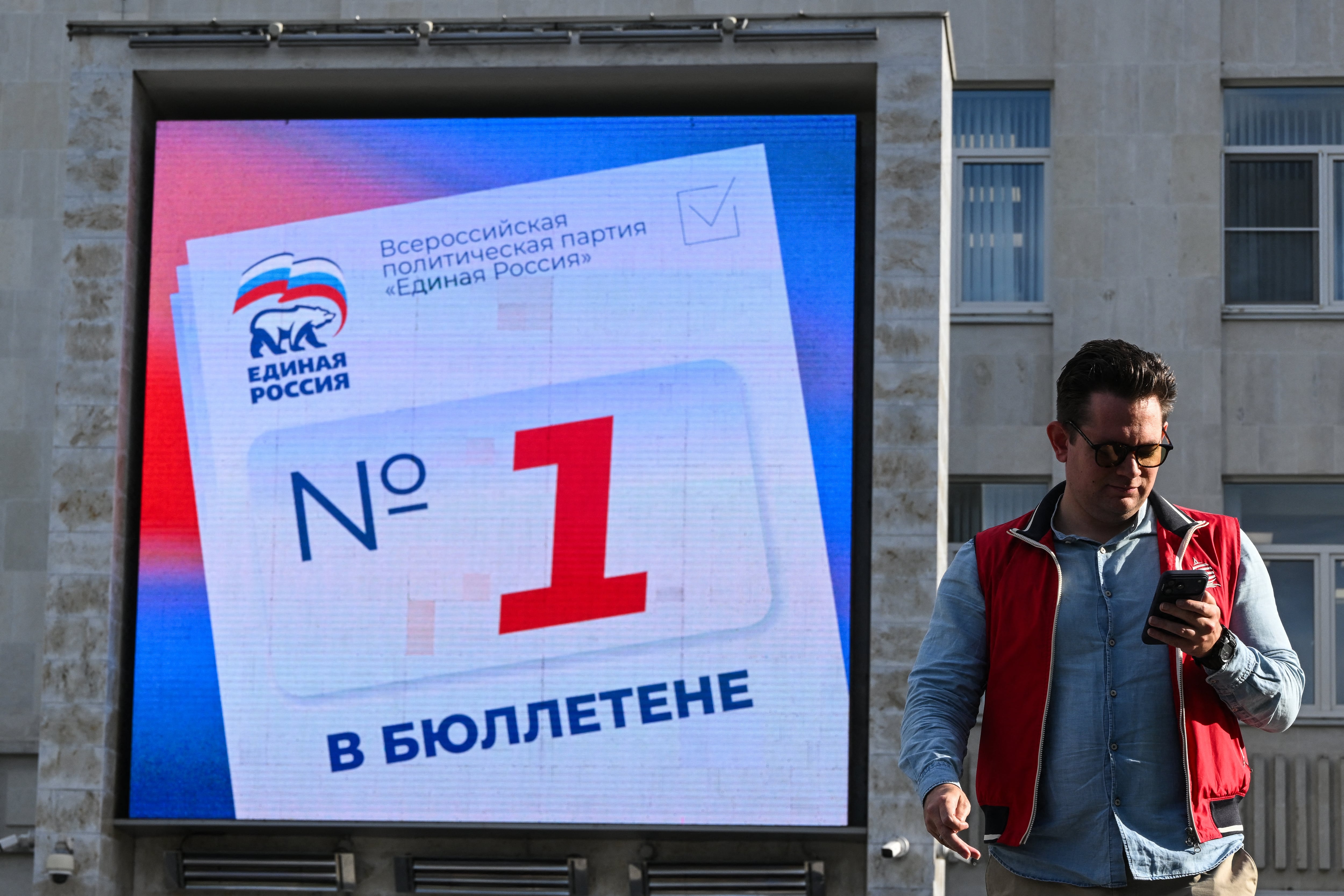 Un hombre camina frente a una pantalla digital en la sede del partido Rusia Unida, en Moscú, que llama a votar por sus candidatos en las elecciones parlamentarias previstas del 18 al 20 de setiembre.