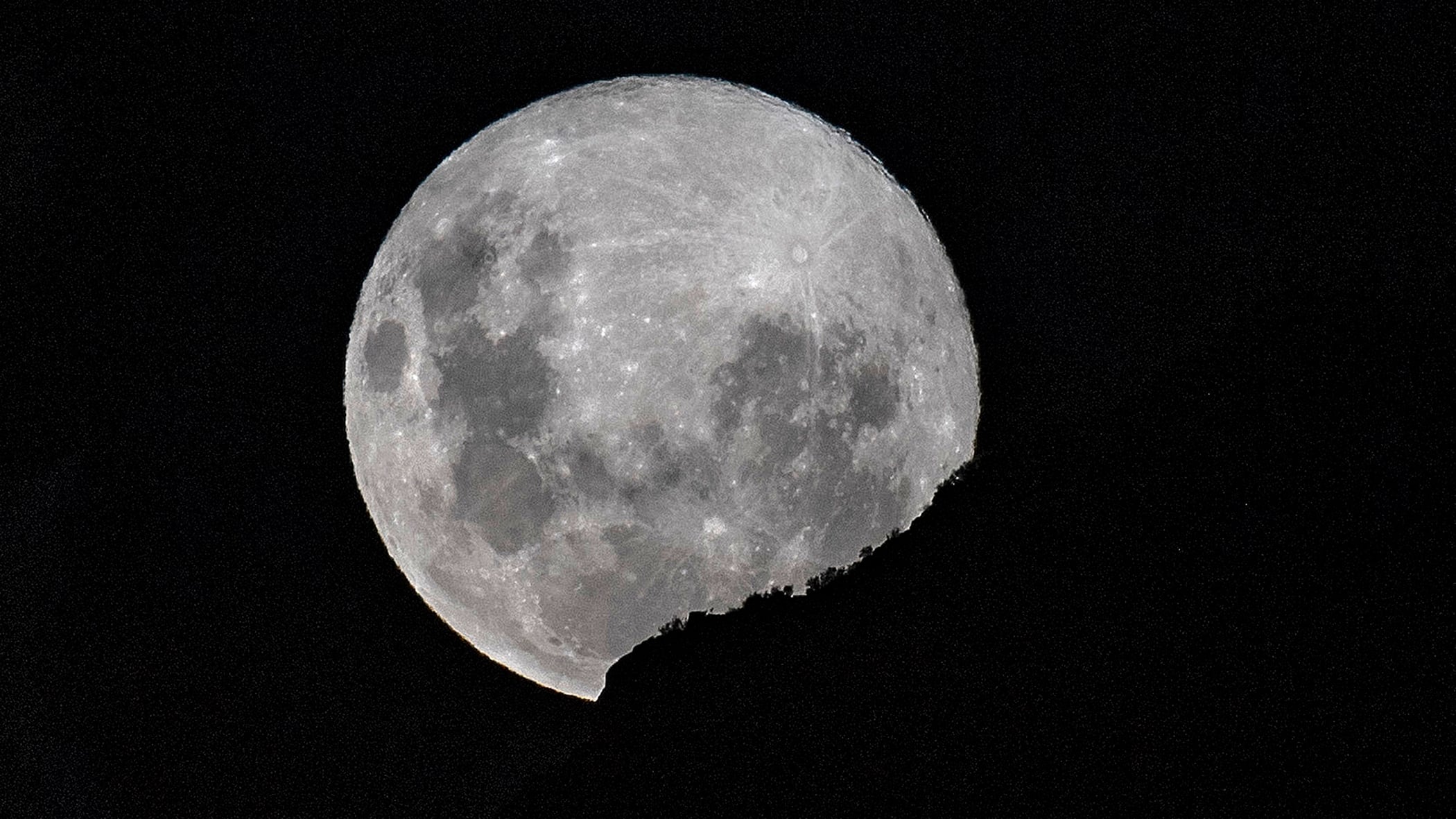 The supermoon rises over Santiago, on April 7, 2020. A supermoon occurs when the moon reaches its closest position to the Earth, known as the perigee, making the satellite appear bigger and brighter than usual. (Photo by Martin BERNETTI / AFP)