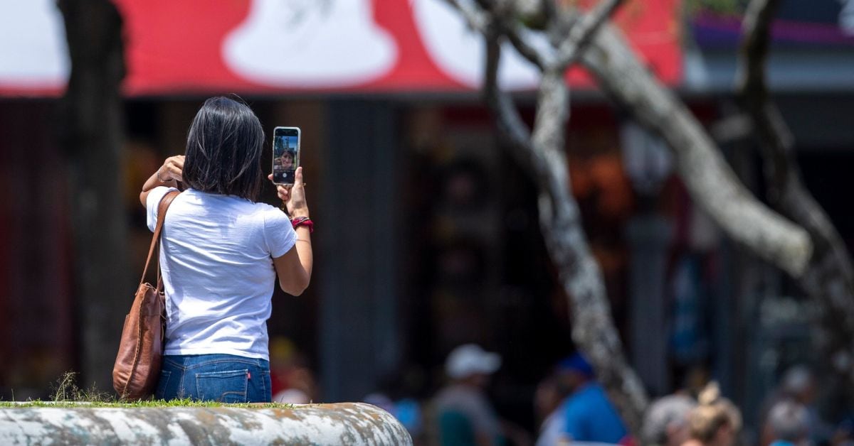 En la imagen una mujer usando un teléfono celular