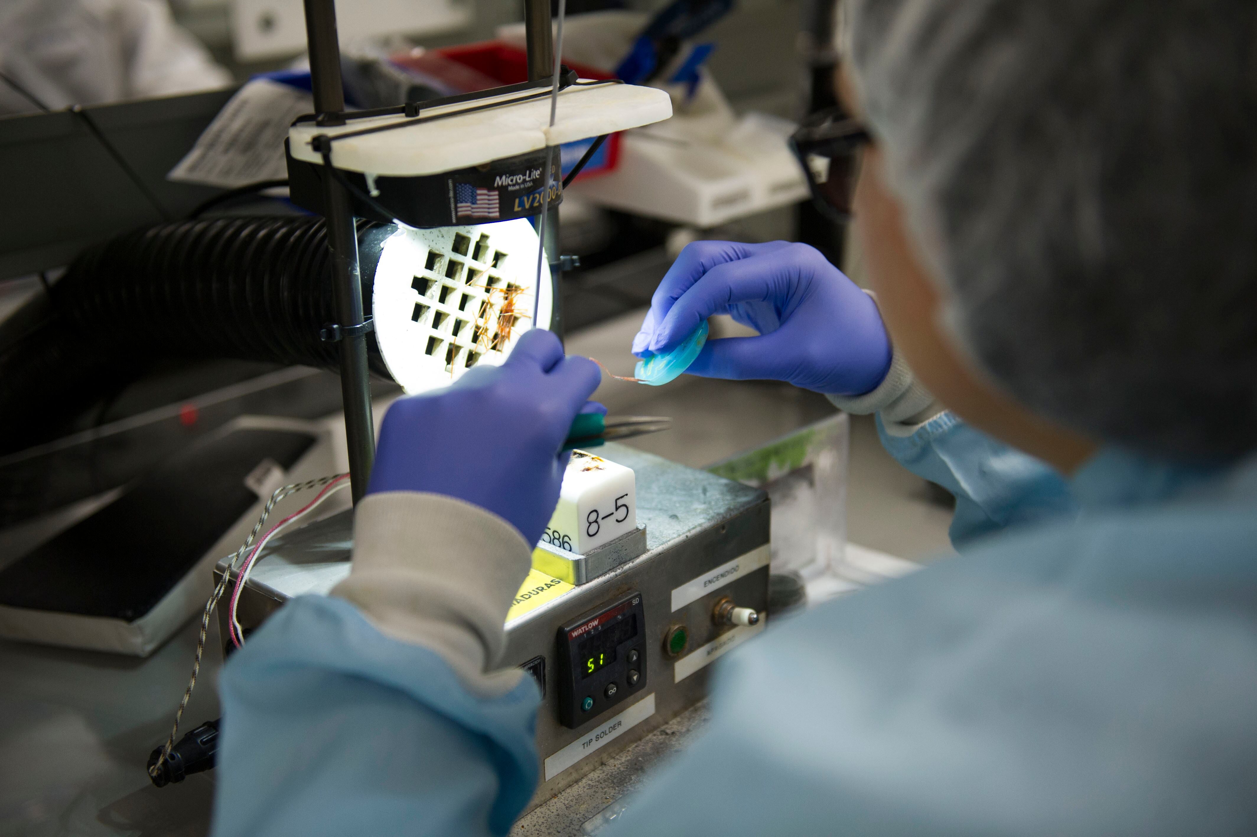 Empleado de Boston Scientific Costa Rica trabaja en la producción de dispositivos médicos en la planta de Coyol, Alajuela, utilizando guantes y equipo especializado.