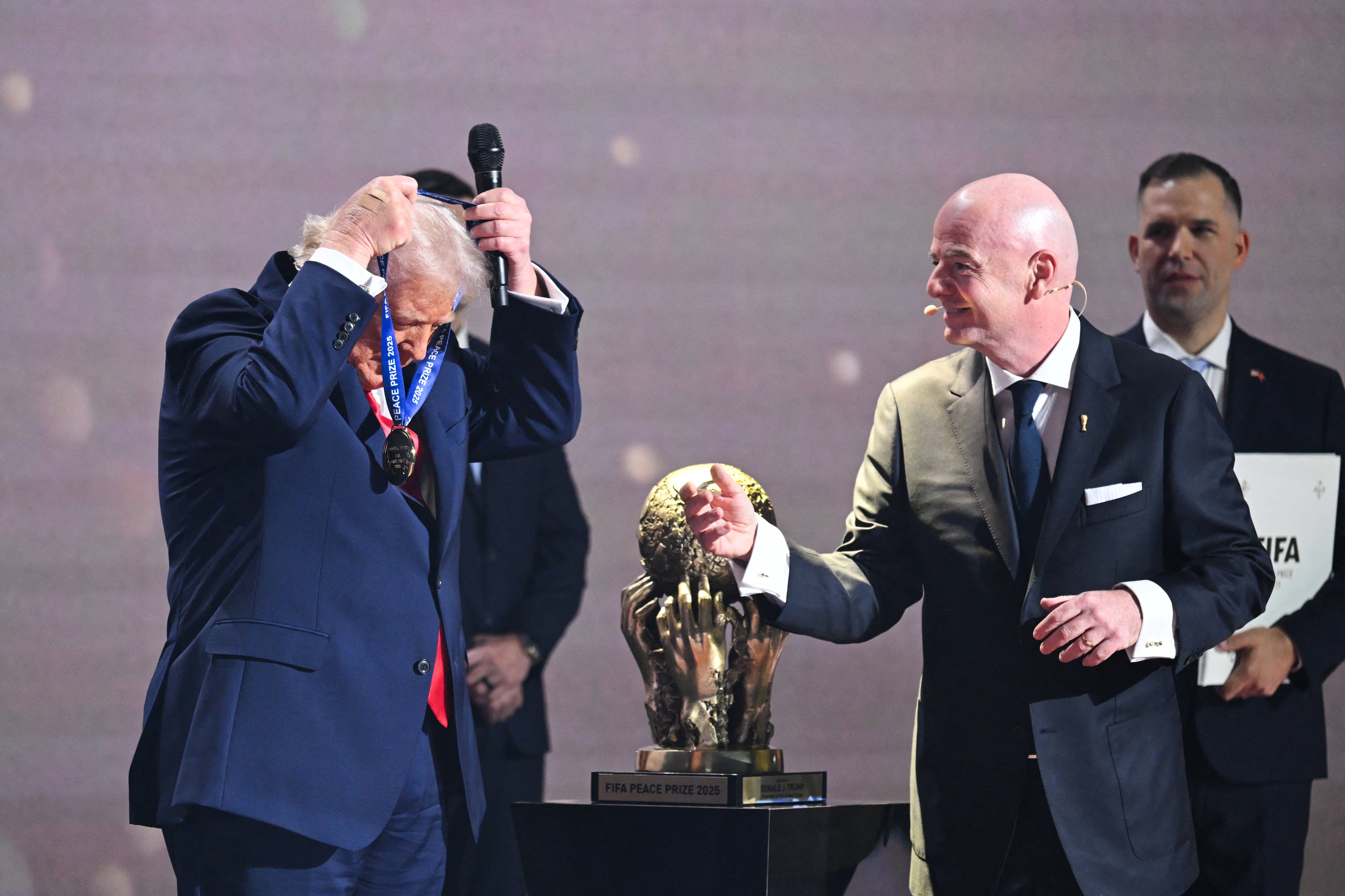 Donald Trump se coloca la medalla que le entregó Gianni Infantino como primer ganador del Premio FIFA de la Paz, durante el sorteo del Mundial 2026 en el Kennedy Center de Washington.