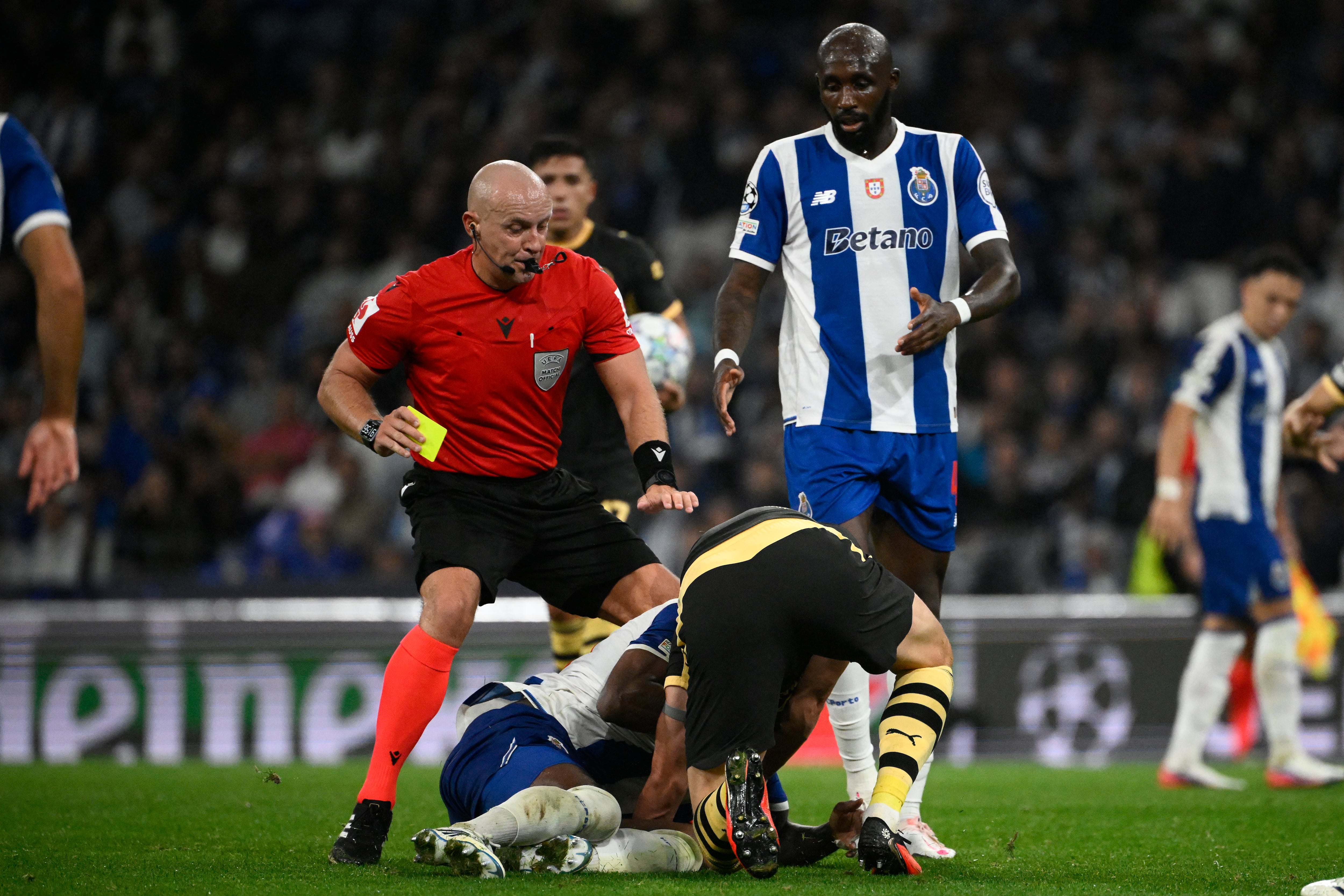 El árbitro polaco Szymon Marciniak trata de separa al delantero del Manchester City, Erling Haaland, y el volante dominicano del Porto, Pablo Rosario, que se enfrascaron en lucha libre en el Estadio Dragao de Portugal.