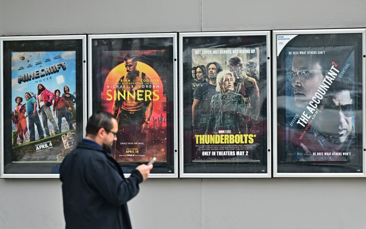 A man walks past movie posters at at AMC Theater in Montebello, California on May 5, 2025. US President Donald Trump said Sunday he was ordering new tariffs on all films made outside the United States, claiming Hollywood was being "devastated" by a trend of US filmmakers and studios working abroad. The announcement comes as the White House is coming under mounting criticism over its aggressive trade policies that have seen Trump impose sweeping tariffs on countries around the globe. (Photo by Frederic J. BROWN / AFP)
