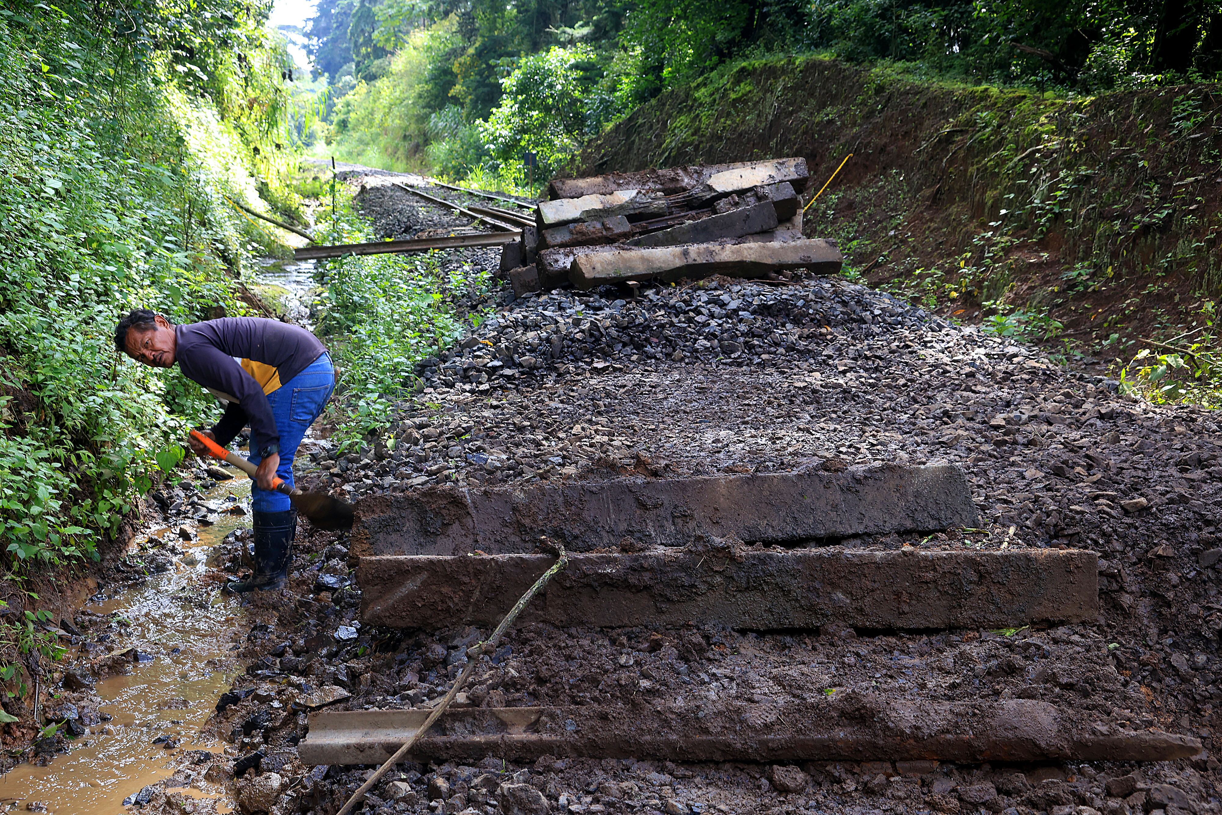 Persona removiendo barro de los durmientes en las reparaciones actuales de la vía férrea en Cartago.
