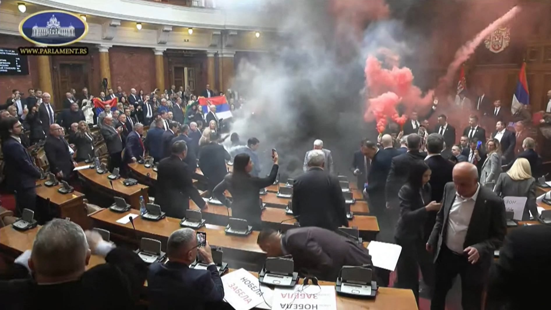This frame grab from handout video footage taken and released by the National Assembly of the Republic of Serbia in Belgrade on March 4, 2025 shows Serbian opposition lawmakers lighting flares and discharging suspected tear gas during the opening day of the spring session of parliament in a sign of support for ongoing anti-corruption protests. The footage shared online showed opposition members holding colourful flares and throwing what appeared to be smoke cannisters during the legislative session. Serbia has been rocked for months by student-led anti-corruption protests following the fatal collapse of a train station roof last year that killed 15 people. (Photo by Handout / National Assembly of the Republic of Serbia / AFP) / RESTRICTED TO EDITORIAL USE - MANDATORY CREDIT "AFP PHOTO / National Assembly of the Republic of Serbia " - NO MARKETING NO ADVERTISING CAMPAIGNS - DISTRIBUTED AS A SERVICE TO CLIENTS