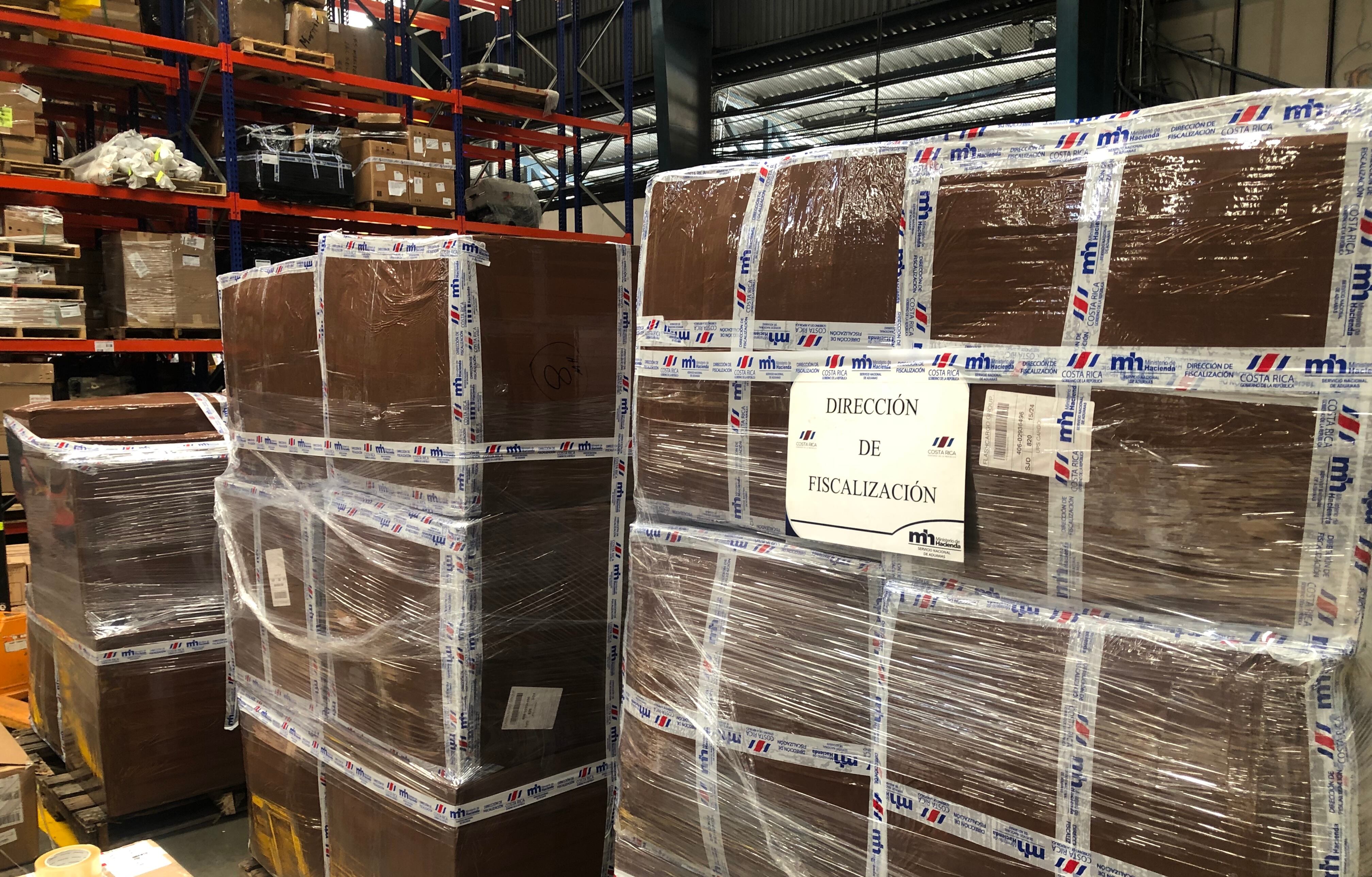 Cajas embaladas en un depósito aduanero, etiquetadas con "Dirección de Fiscalización". Representan la disminución de controles aduaneros señalada por un informe de la Contraloría General de la República.