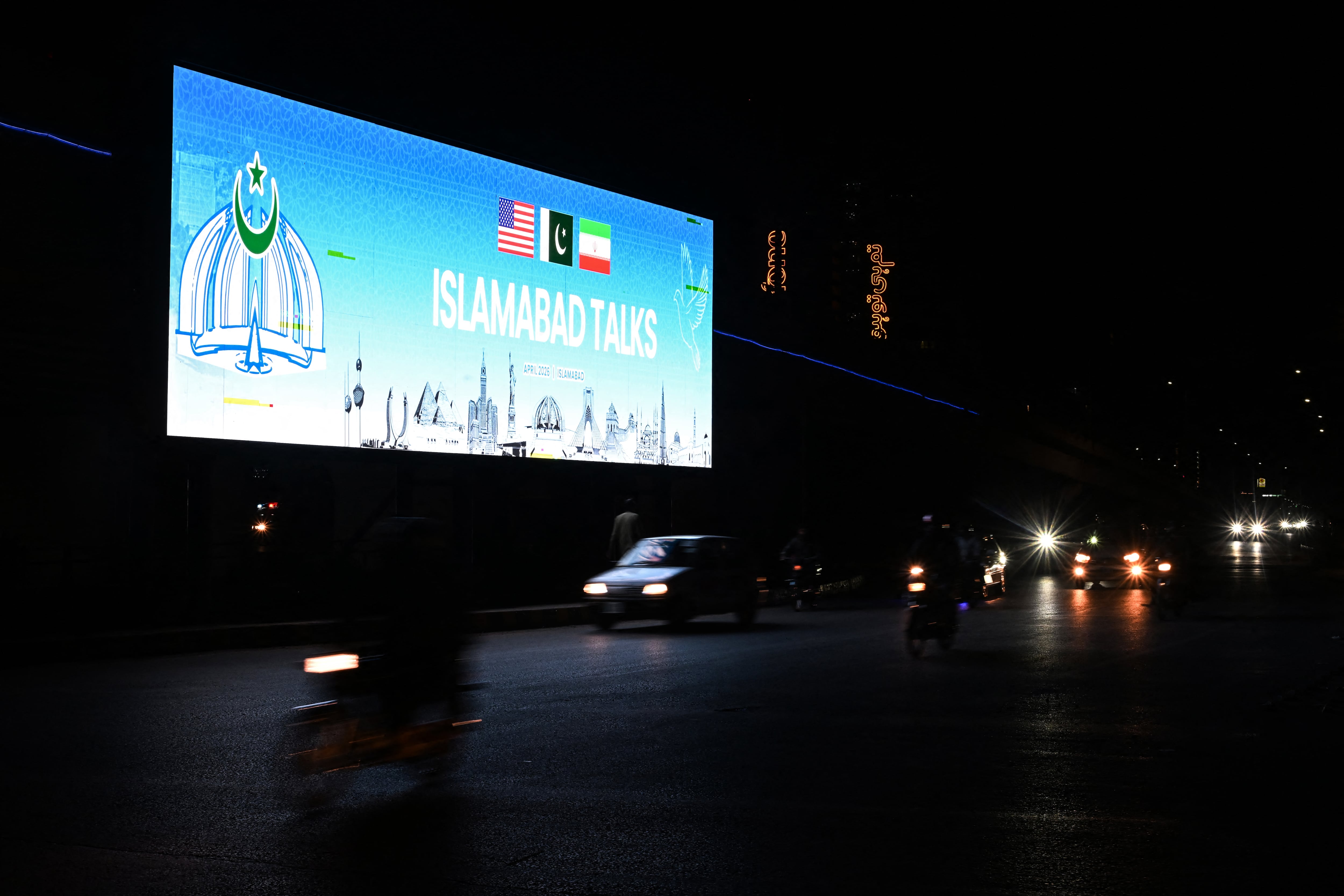 Un peatón observa una pantalla digital mientras Estados Unidos e Irán mantienen conversaciones de paz en Islamabad, el 11 de abril de 2026.