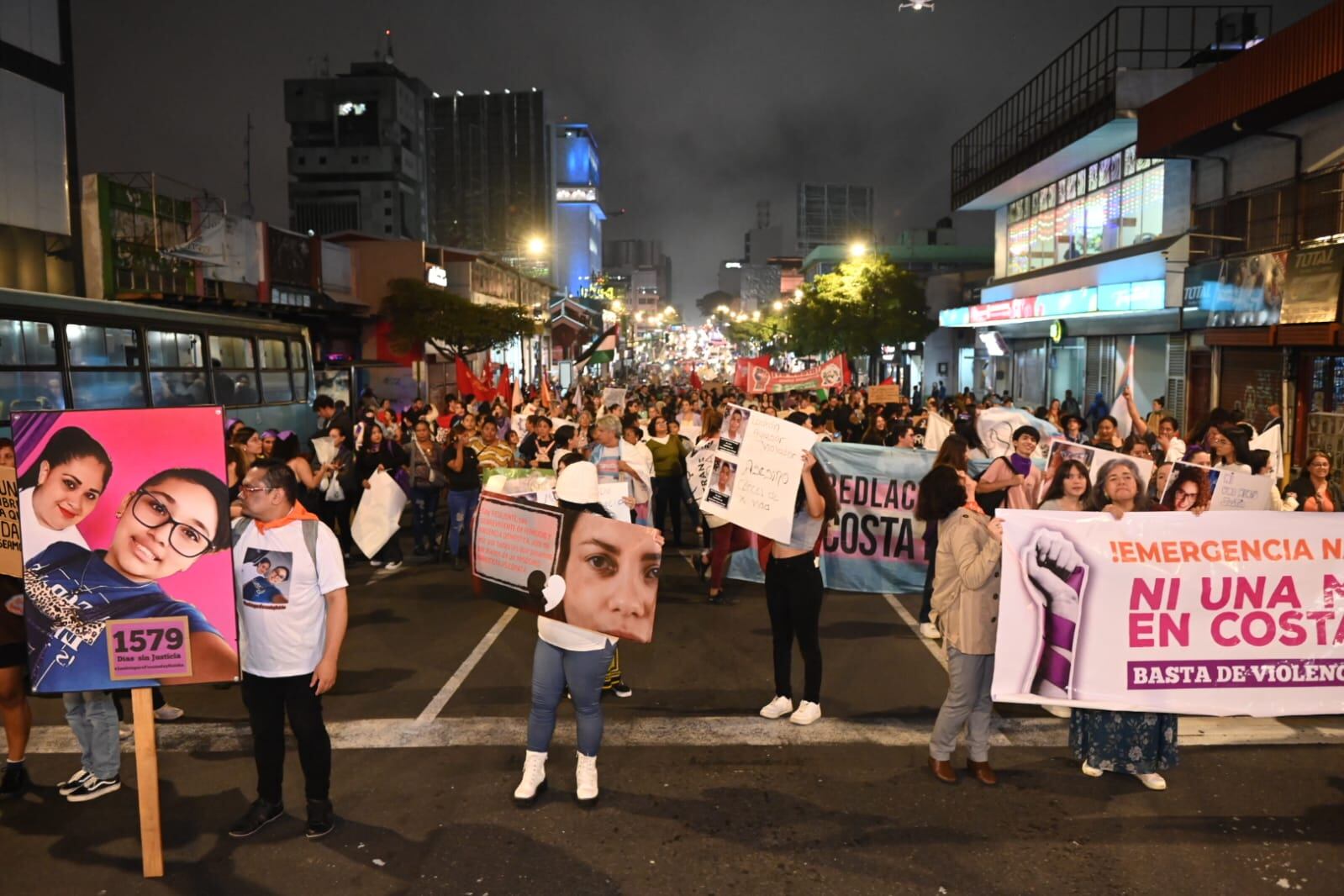 Una multitud marcha por la avenida segunda de San José, encabezados por participantes con carteles y mantas que recuerdan a las mujeres víctimas de femicidios.