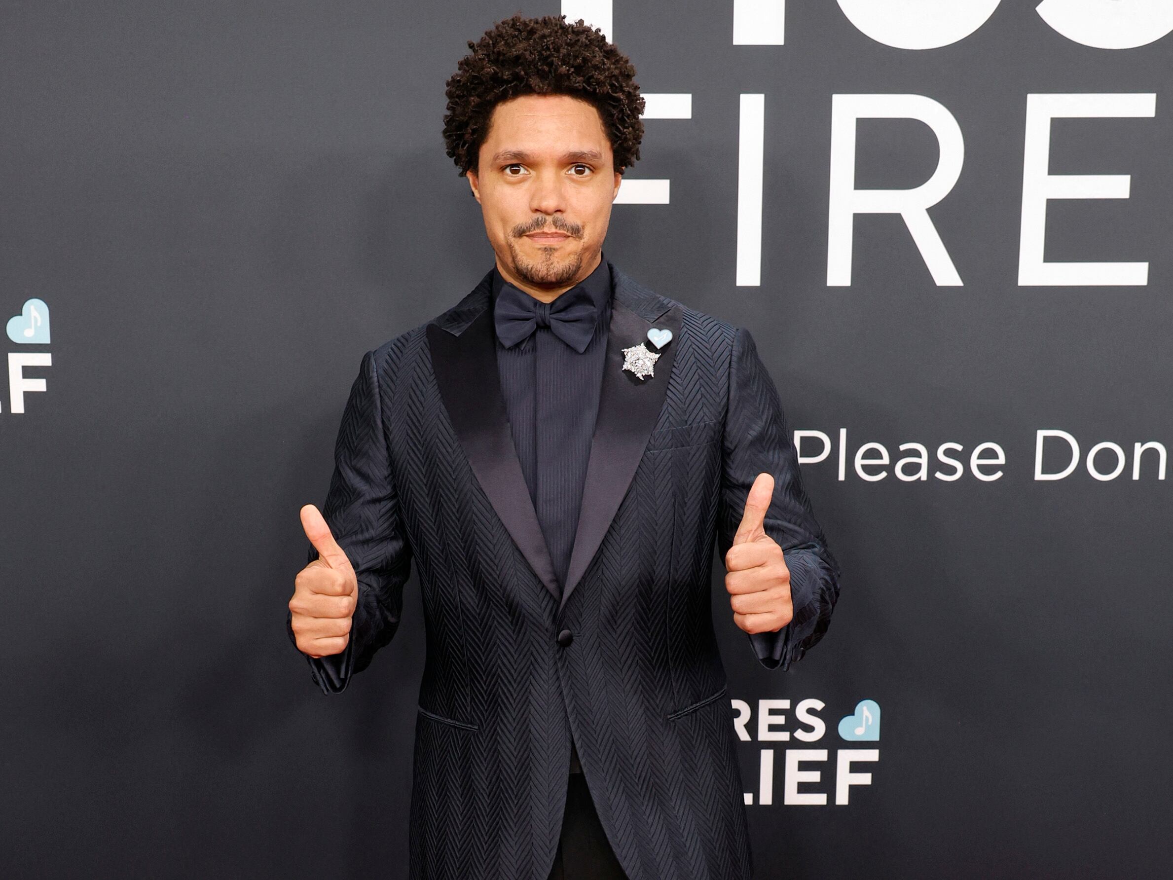 Trevor Noah saluda con los dos pulgares en la alfombra roja de los Grammy 2025