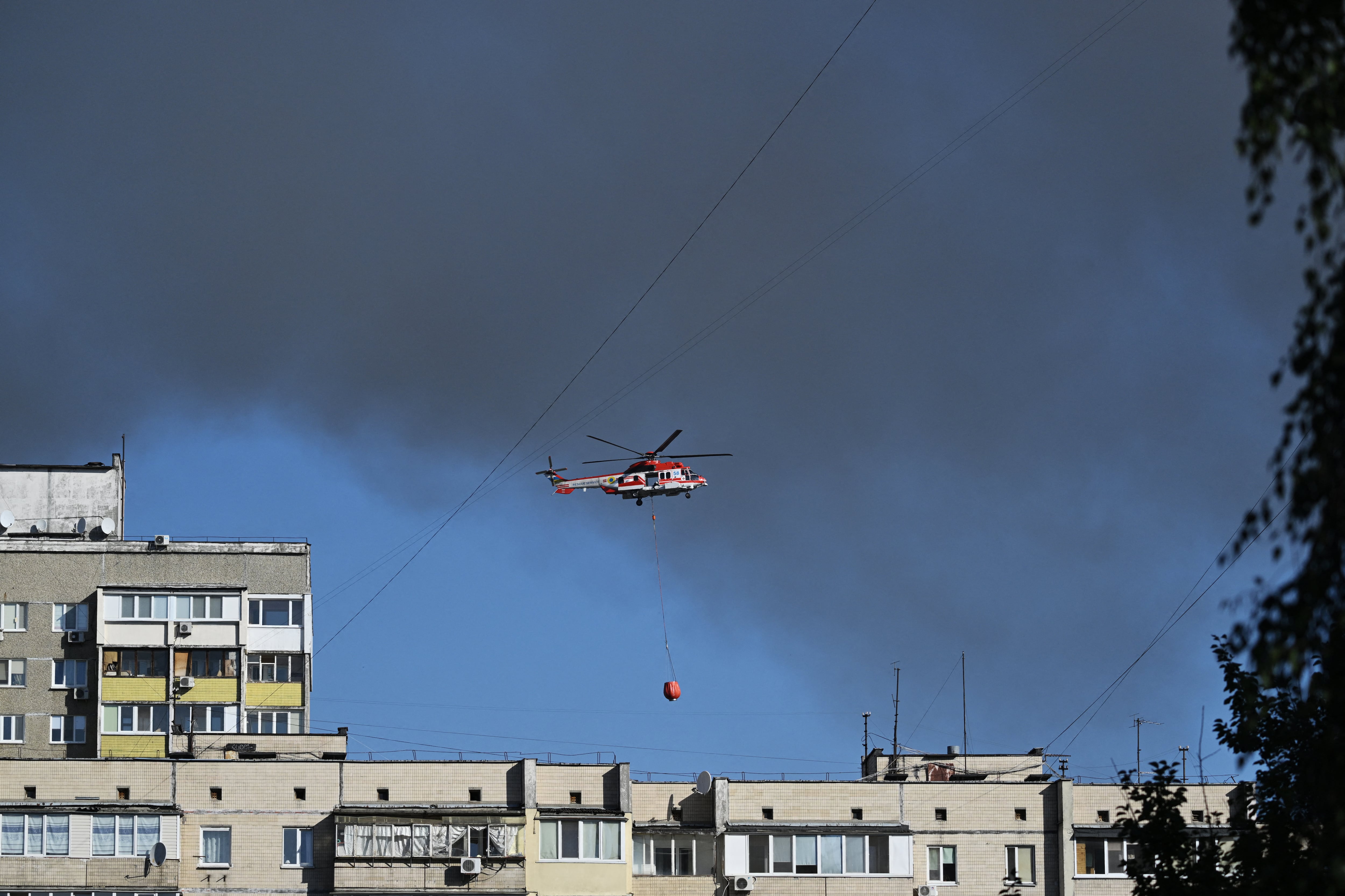 Un helicóptero de bomberos sobrevuela Kyiv mientras los rescatistas trabajan en edificios residenciales dañados por la mayor ofensiva aérea de Rusia hasta la fecha. (Foto: Genya Savilov / AFP)