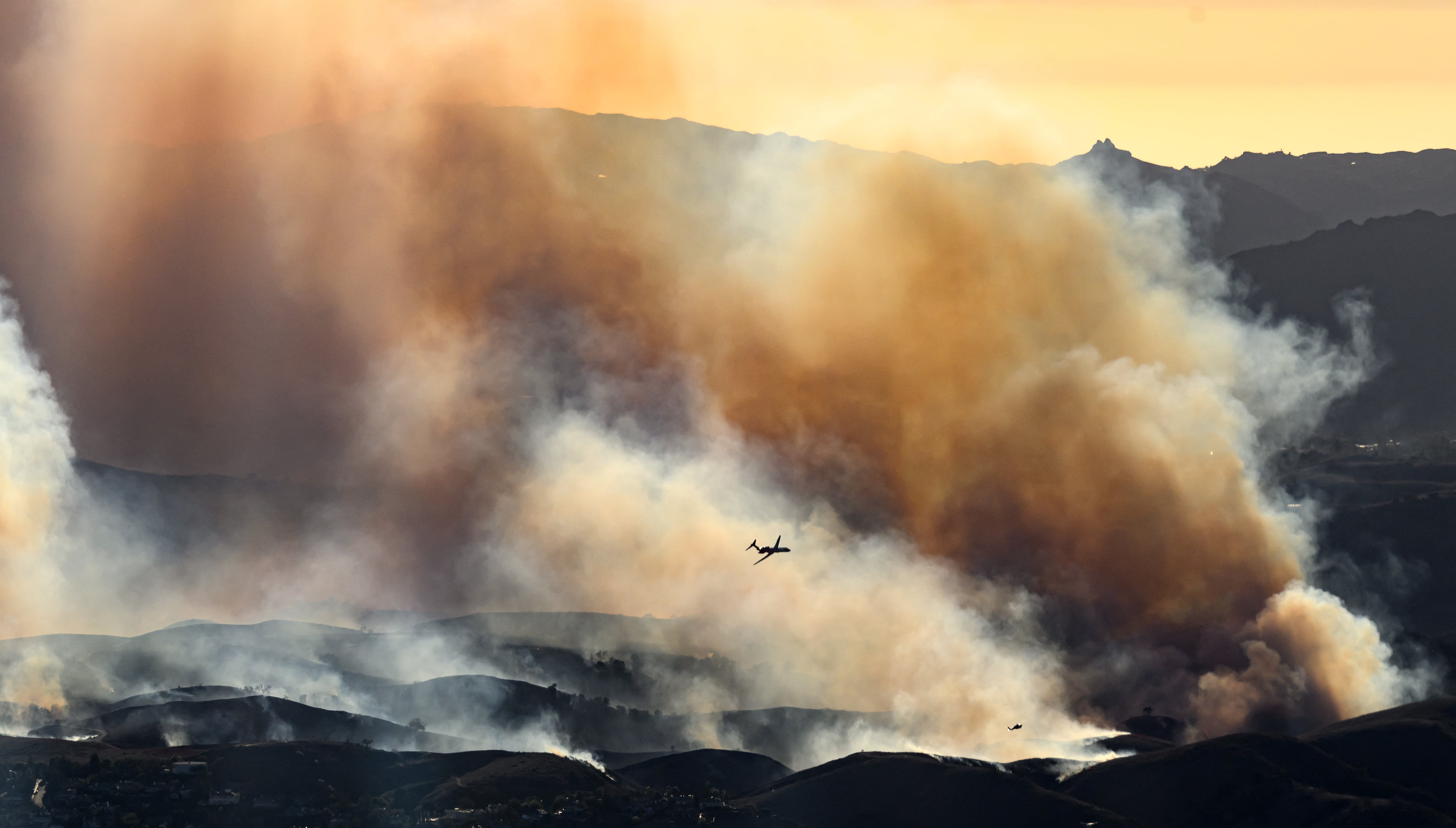 En esta vista aérea tomada desde un helicóptero, un avión cisterna se prepara para arrojar retardante de fuego sobre el incendio Kenneth en el área de Calabasas en el condado de Los Ángeles, California.