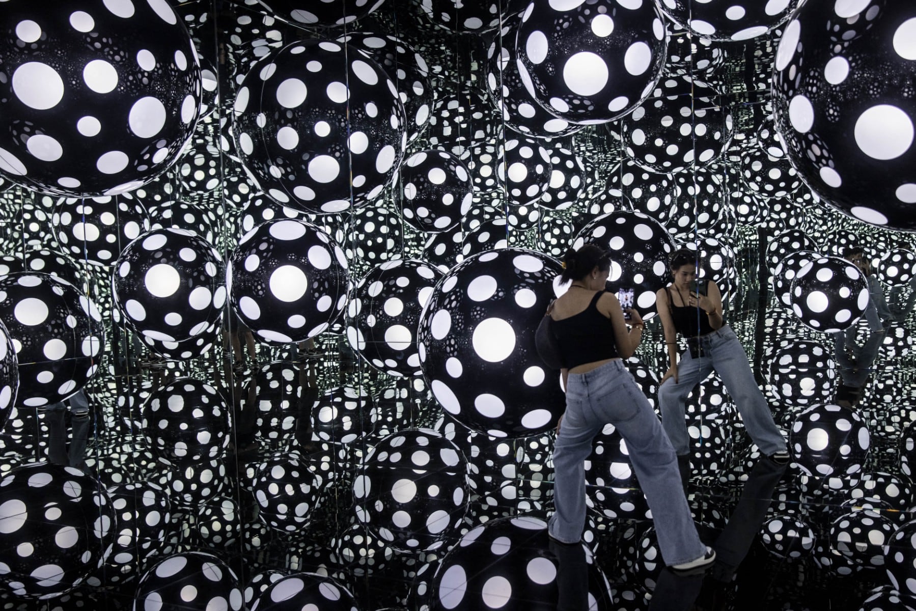 Una mujer toma fotografías de una instalación artística titulada Dots Obsession – Aspiring to Heaven’s Love, de la artista Yayoi Kusama, con sus característicos lunares y espejos reflectantes, en Hong Kong, el 4 de agosto de 2023.