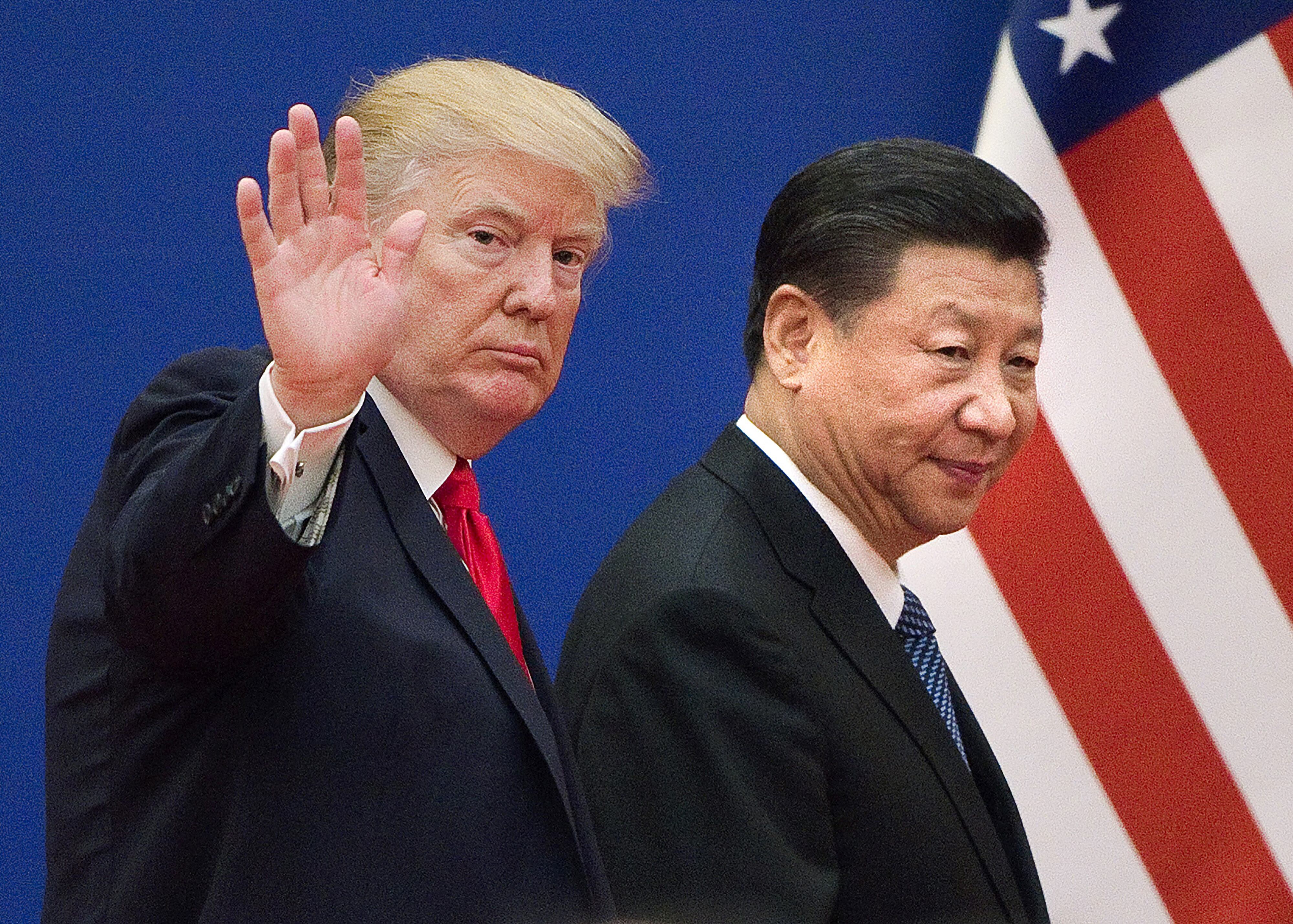 El expresidente de EE. UU., Donald Trump, y el presidente chino, Xi Jinping, caminan juntos en un evento oficial, con la bandera estadounidense de fondo.