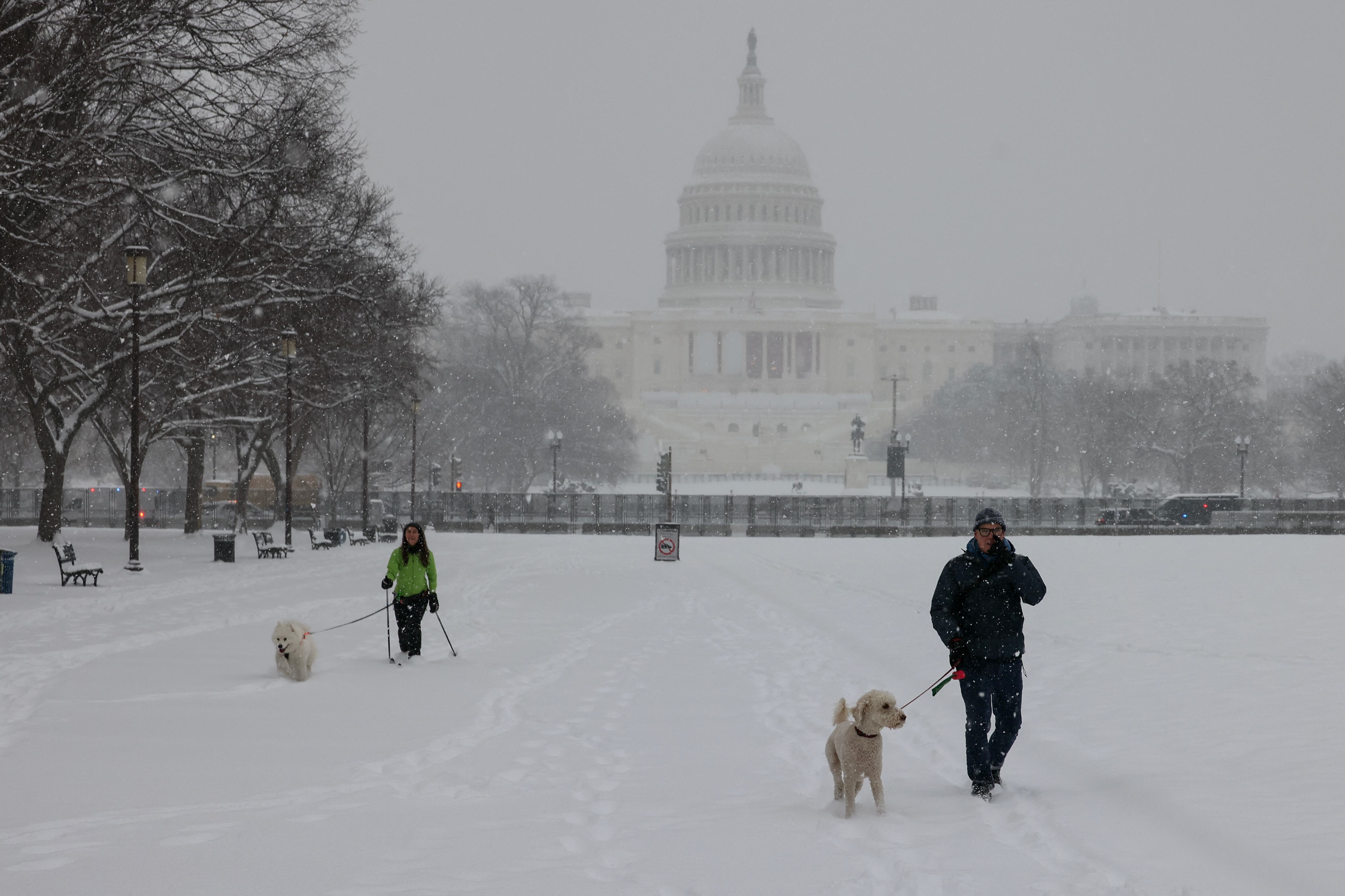Personas pasean perros por el National Mall bajo una fuerte nevada causada por una tormenta invernal en Washington, DC, el 6 de enero de 2025.